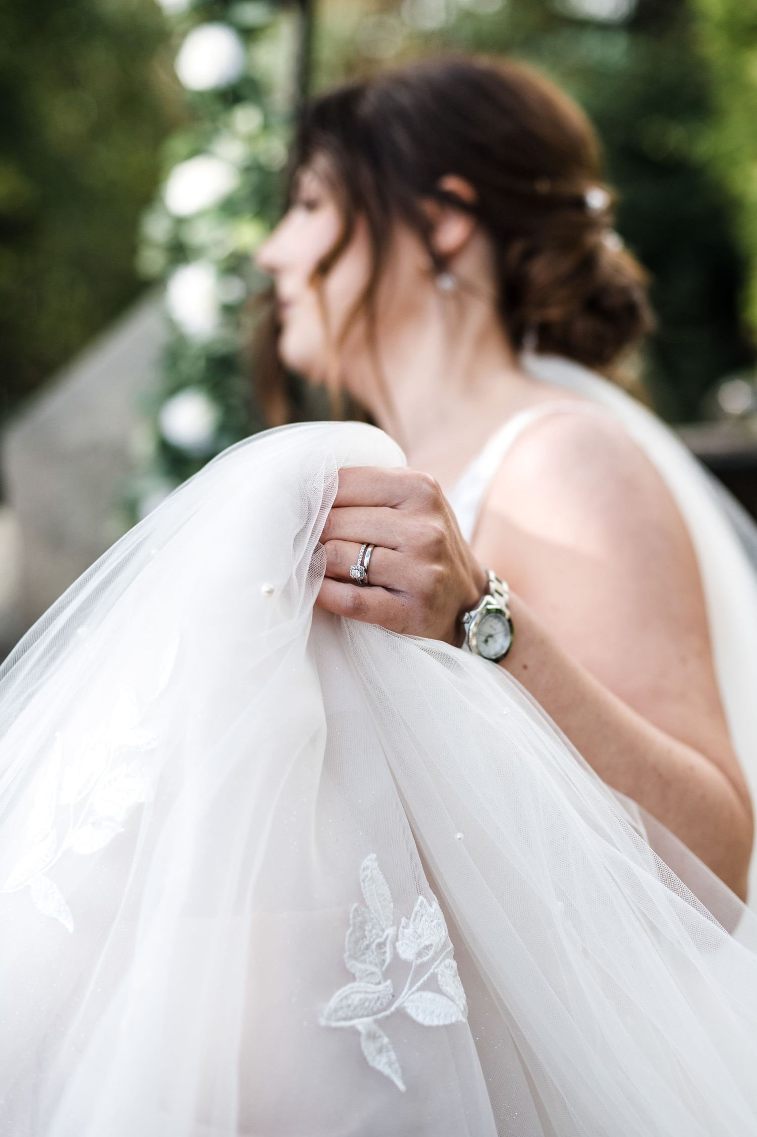 Close-up profile shot showing wedding ring and delicate lace details on bridal gown.
