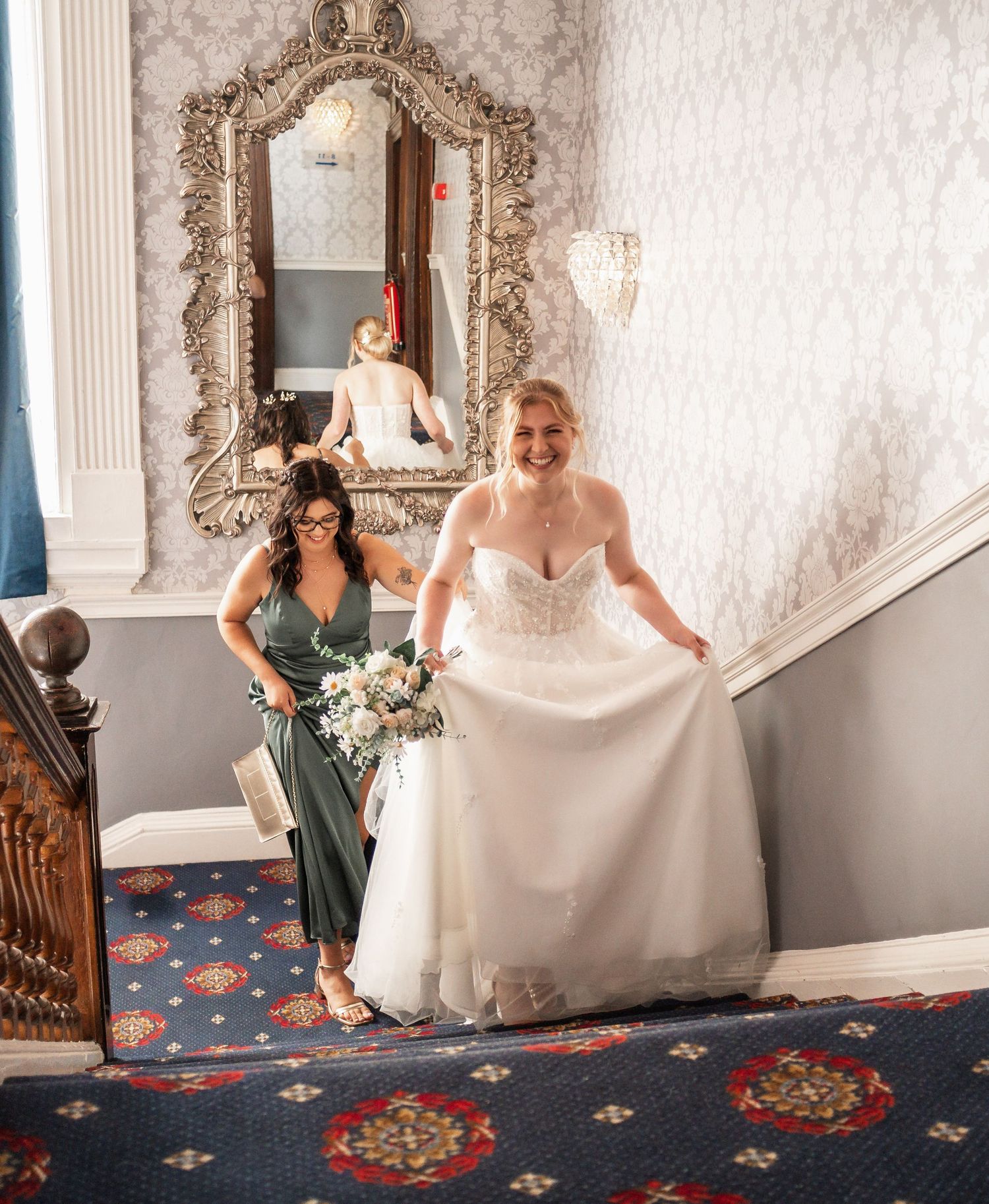 Wedding preparations on staircase with ornate mirror and patterned carpet.