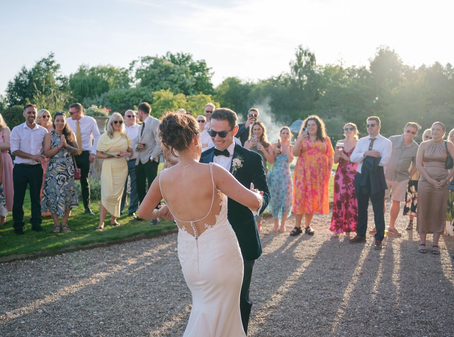 Wedding guests creating pathway during sunset outdoor celebration.