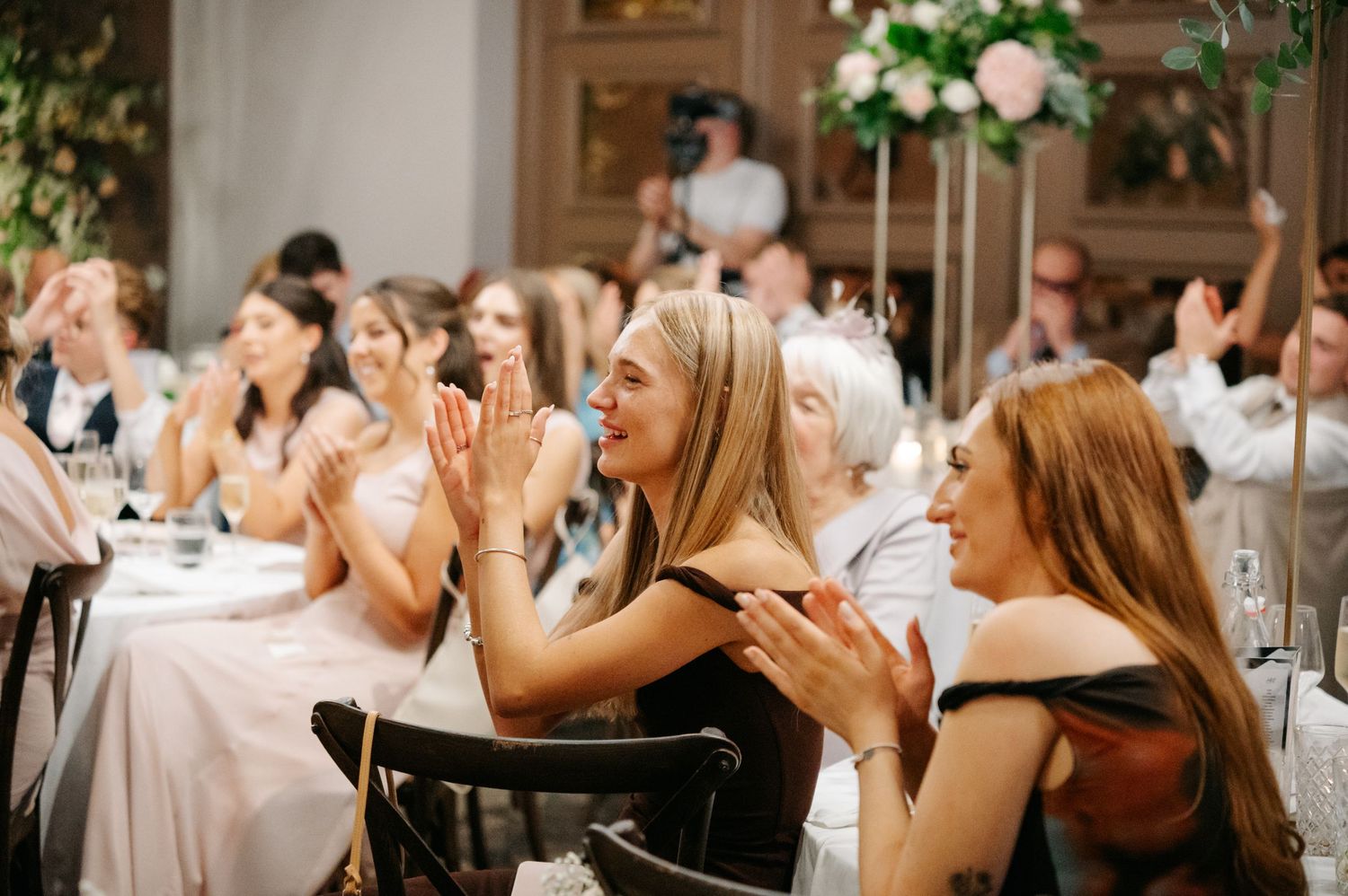 Wedding guests clapping and celebrating during reception festivities.