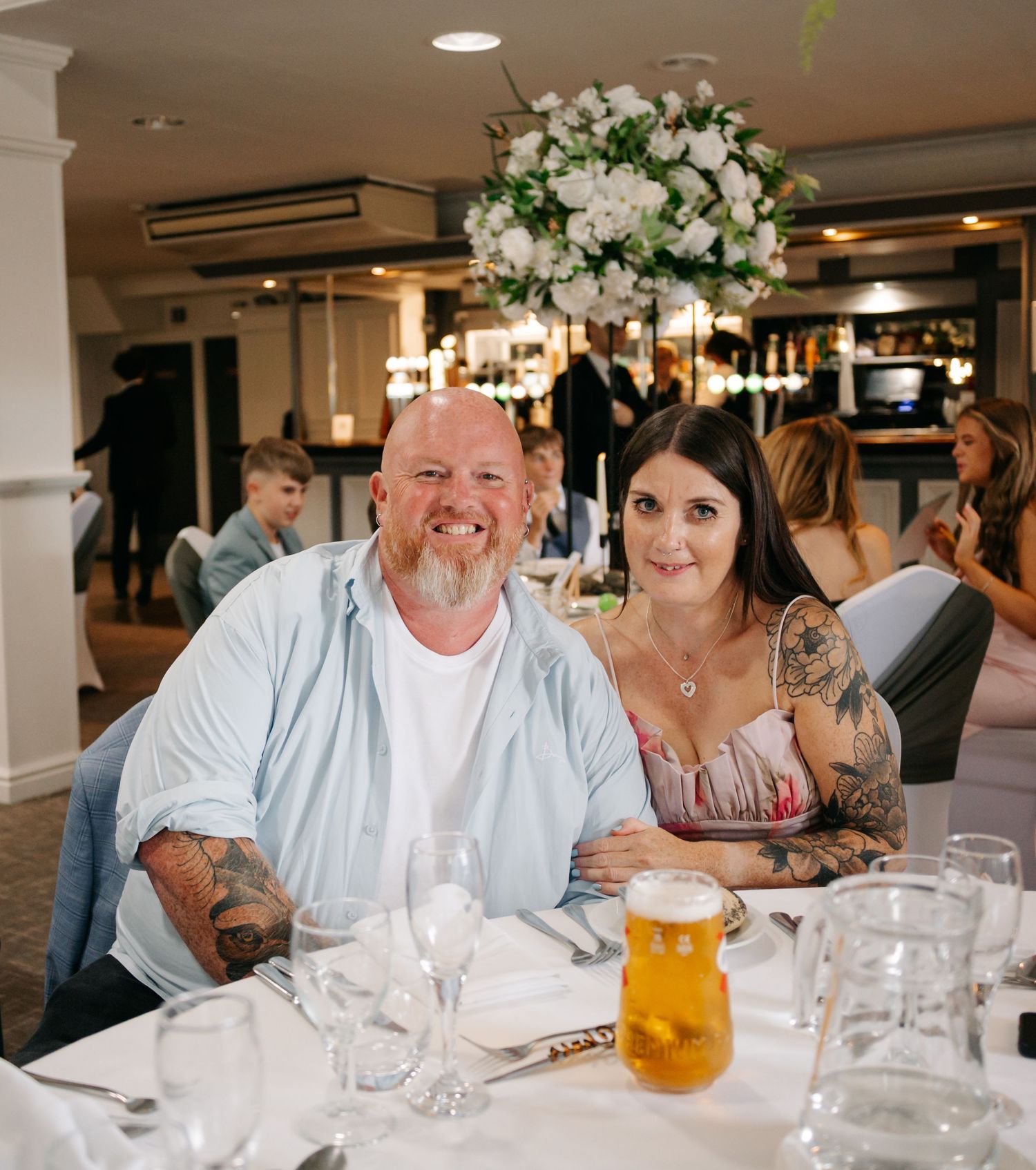 Wedding reception guests enjoying drinks and conversation at decorated indoor venue.