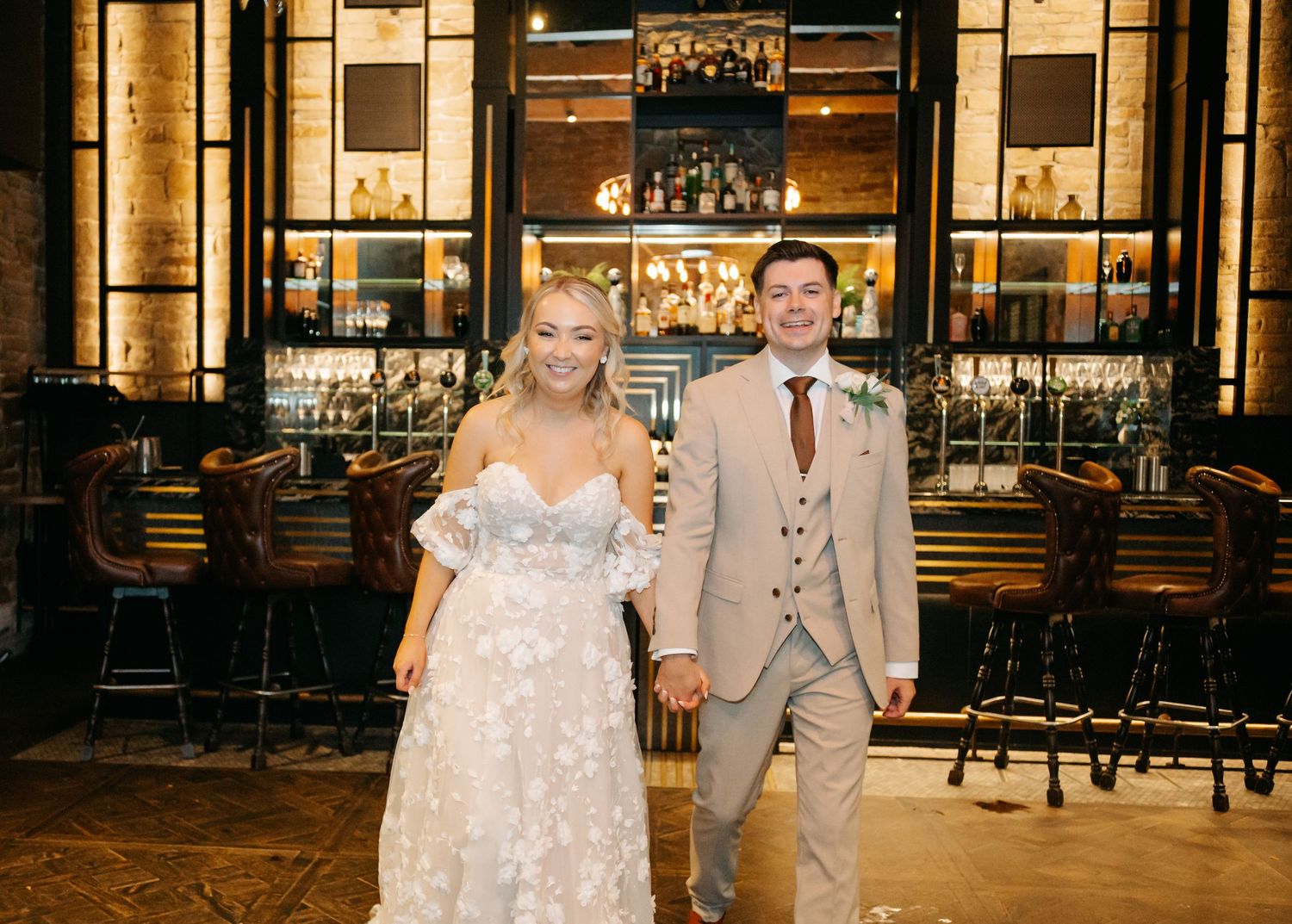 Wedding couple posing in front of an elegant venue with warm lighting.