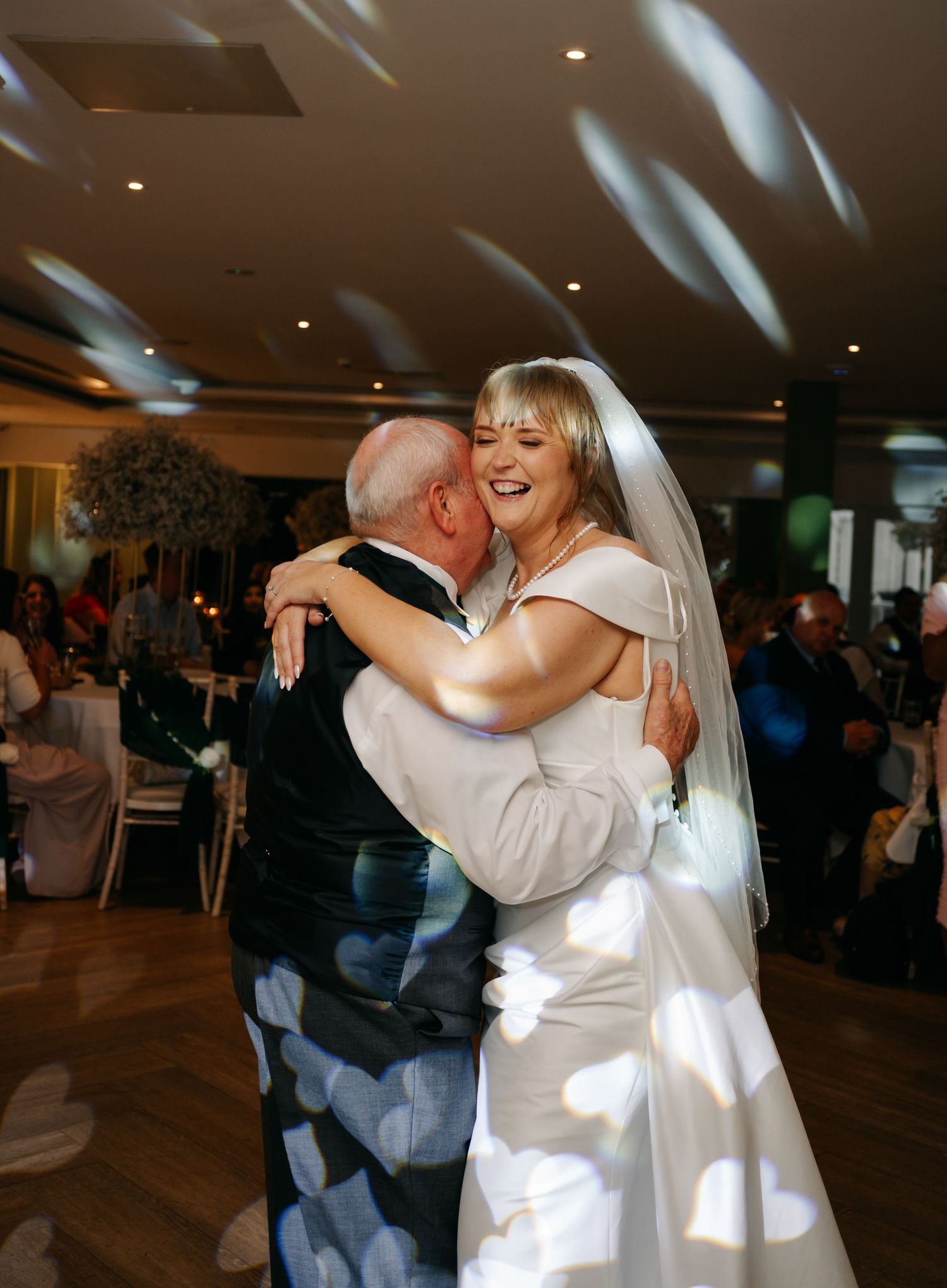 Wedding celebration moments showing dancing and embraces on a wooden dance floor.