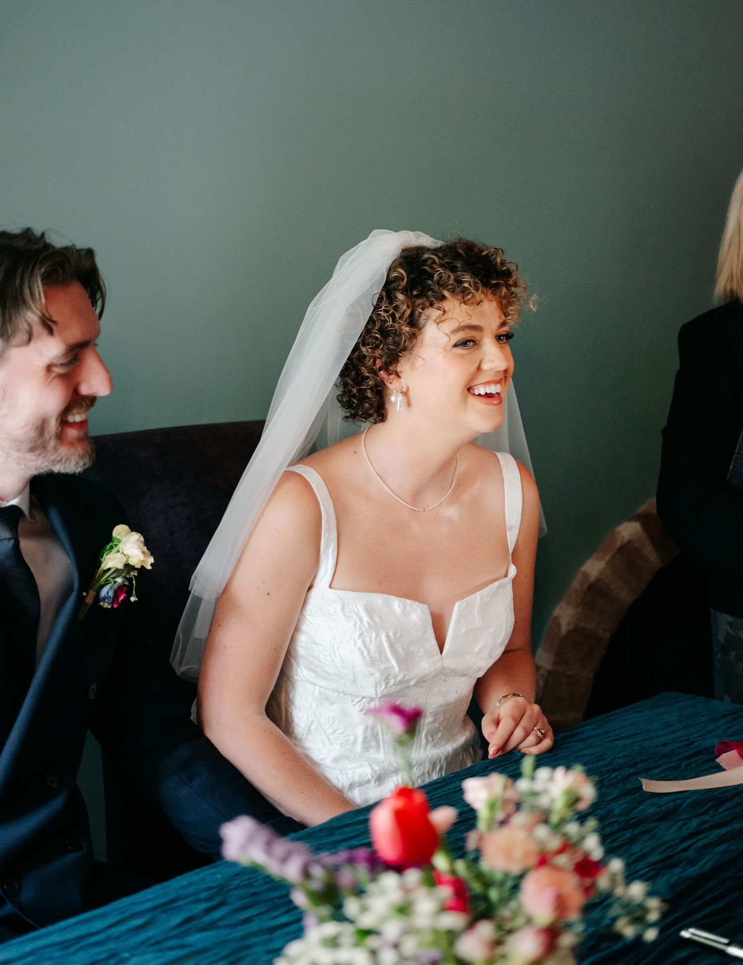 Wedding party members share joyful laughter during candid moments at the reception.