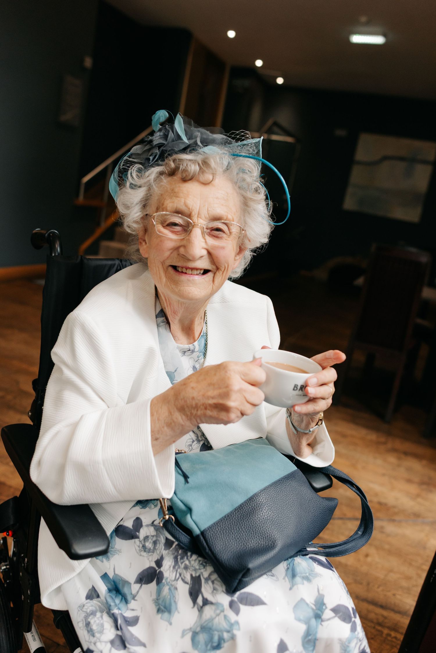 Joyful guest in white jacket enjoying tea during wedding celebration.