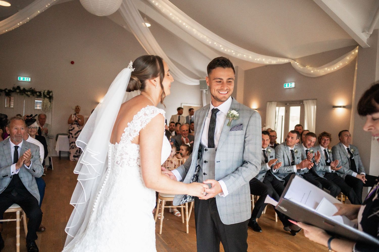 A couple shares a joyful moment during their wedding ceremony in an elegantly draped reception hall.