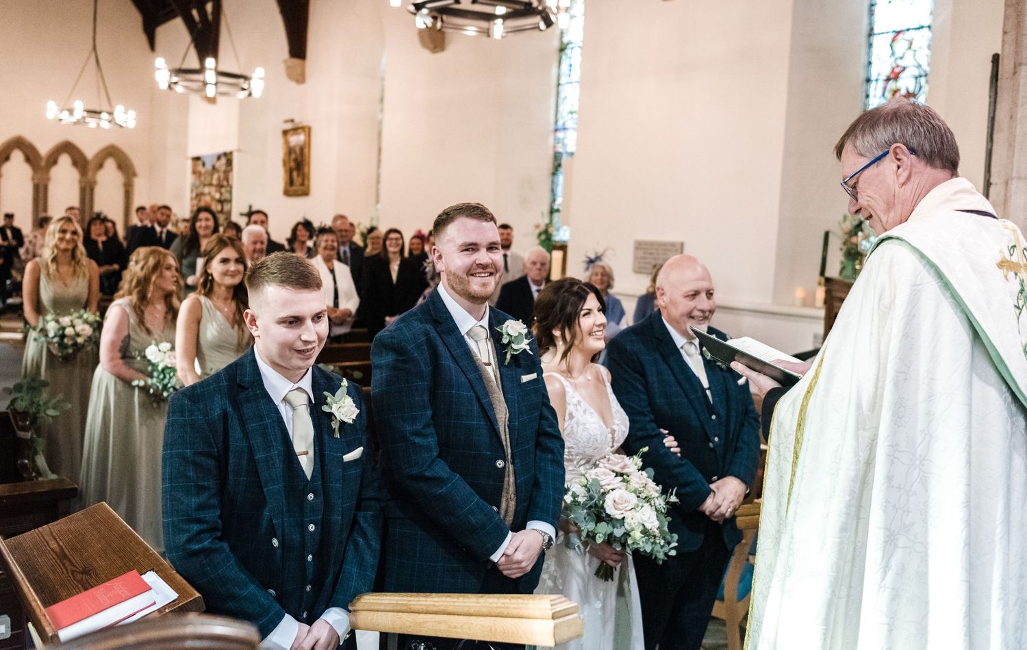 Religious wedding ceremony with guests and officiant in traditional church interior.
