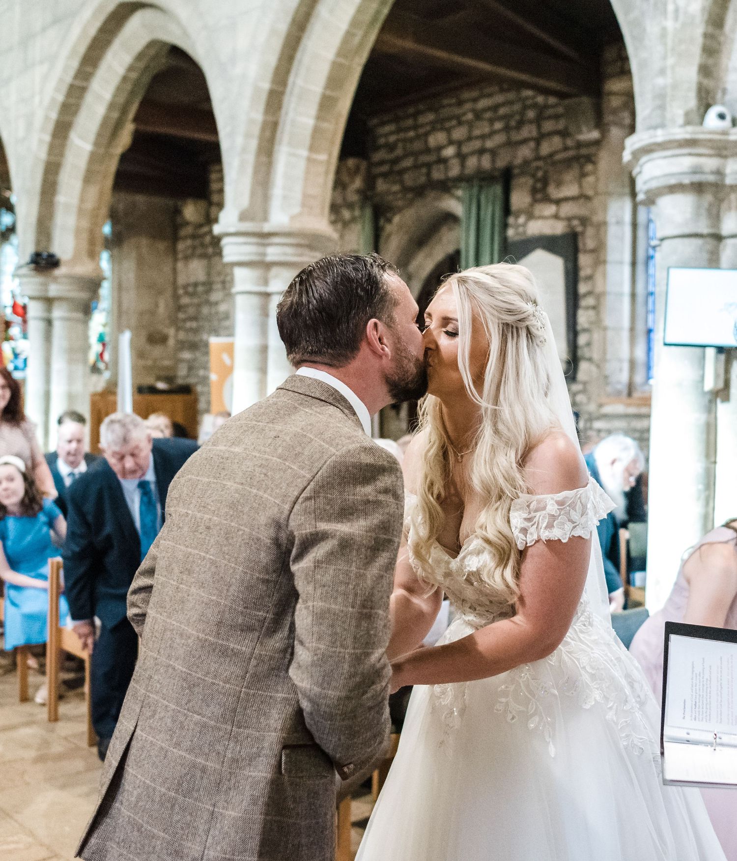 Romantic moment during church wedding ceremony under stone arches.