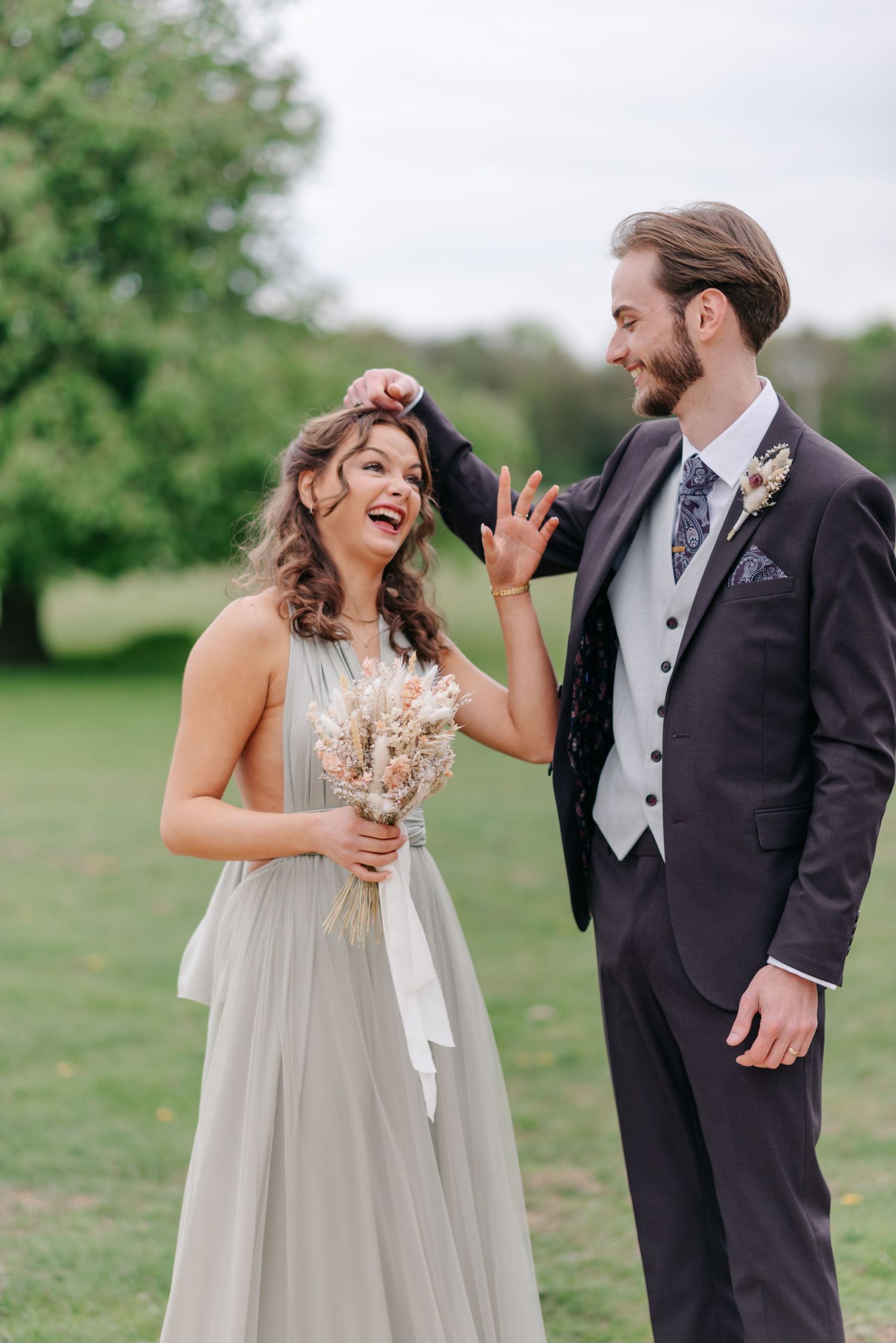 A candid wedding moment captured outdoors with natural greenery and soft lighting.