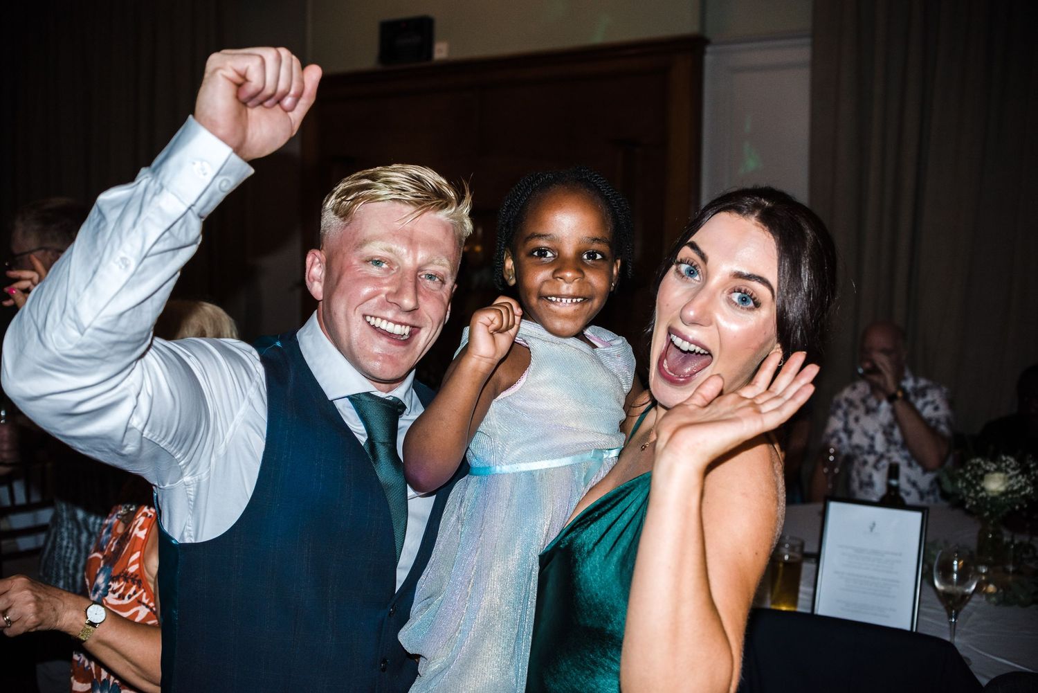 Joyful party guests celebrating and posing playfully at a wedding reception.