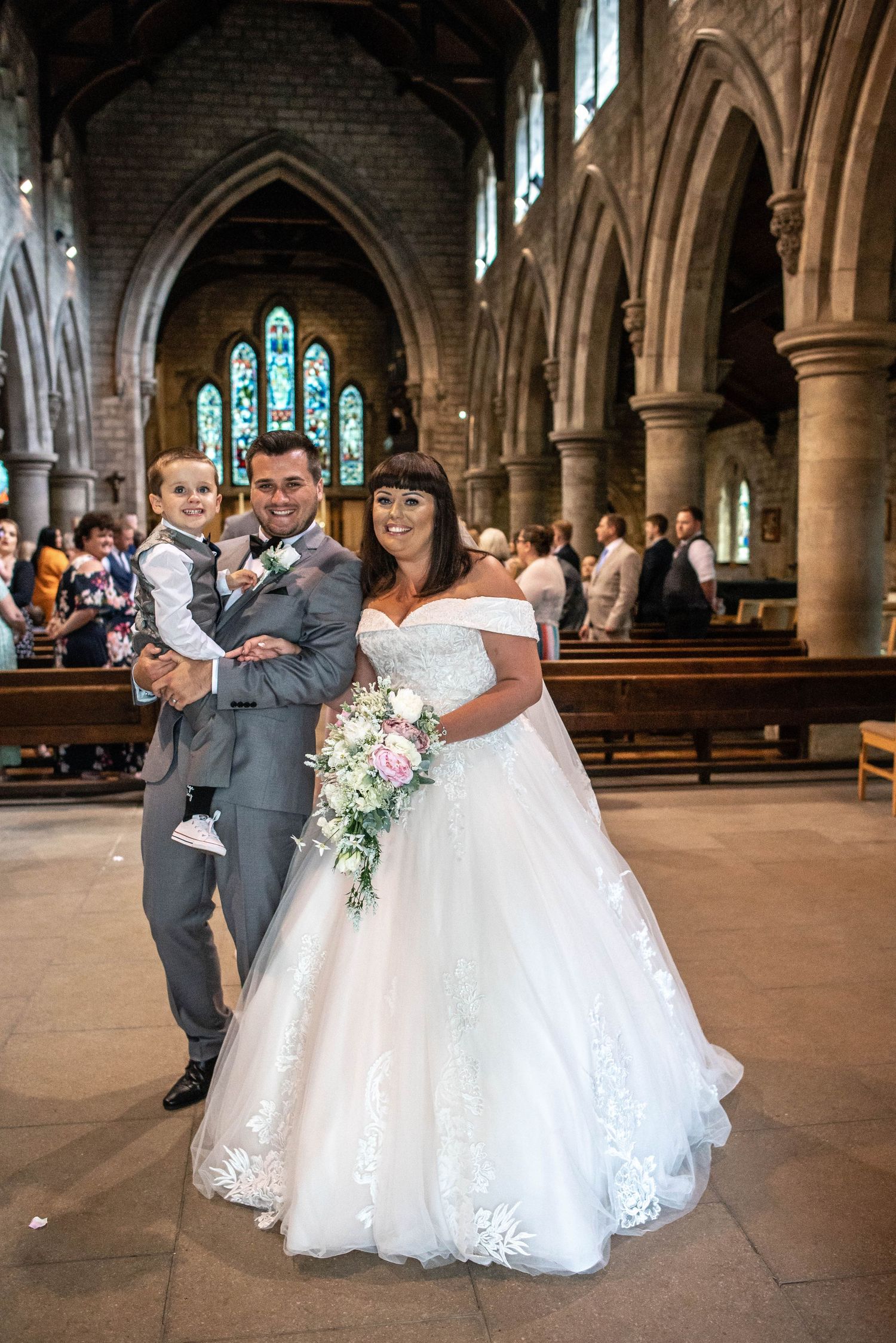 Wedding ceremony photo in a beautiful stone church with gothic architecture and stained glass windows.