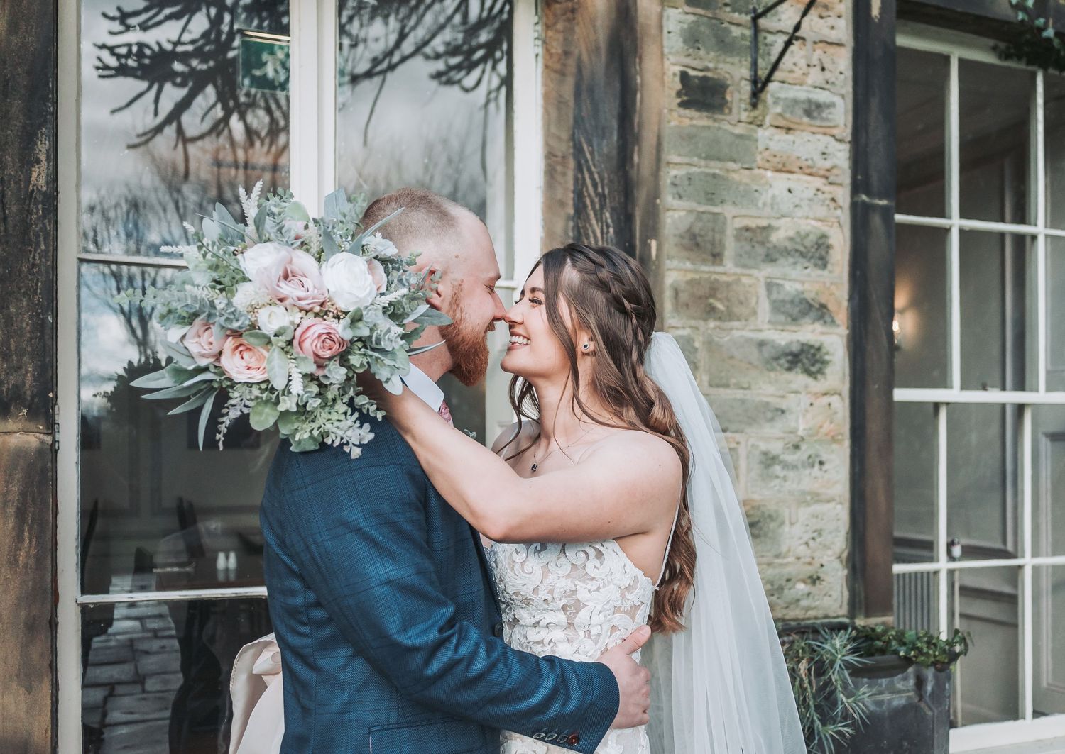 Sweet wedding couple sharing a playful moment with a beautiful floral bouquet.