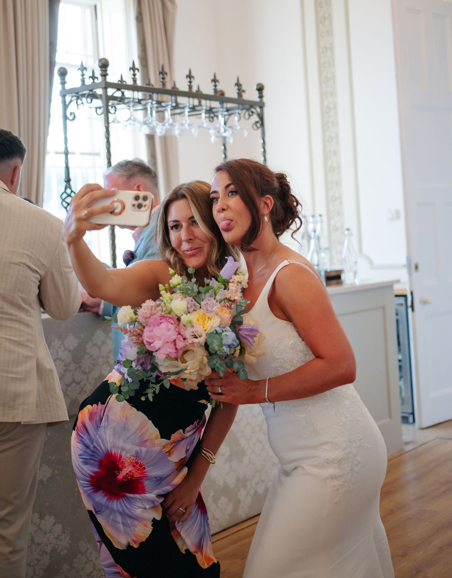 Wedding celebration with colorful bouquets and champagne toasts in an elegant white room.