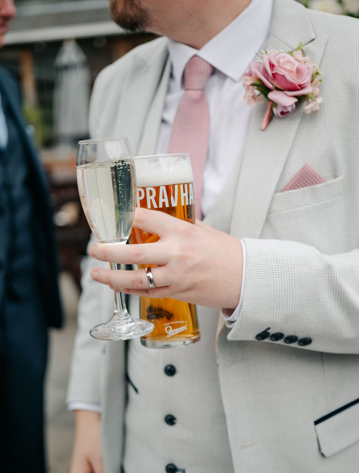 Wedding party members in gray suits hold glasses of beer during reception celebration.