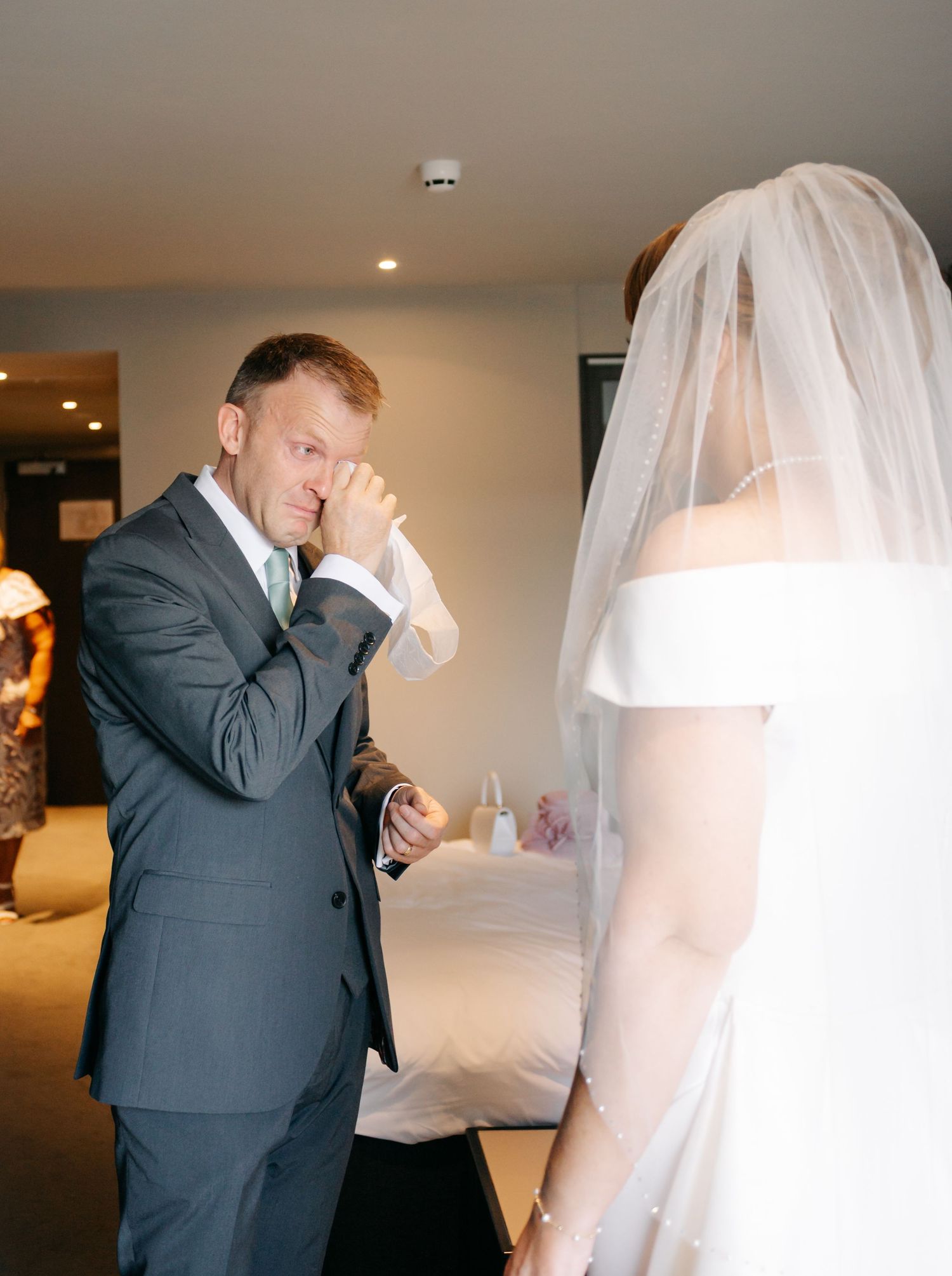 Emotional first look moment between bride and wedding party member in a hotel hallway.
