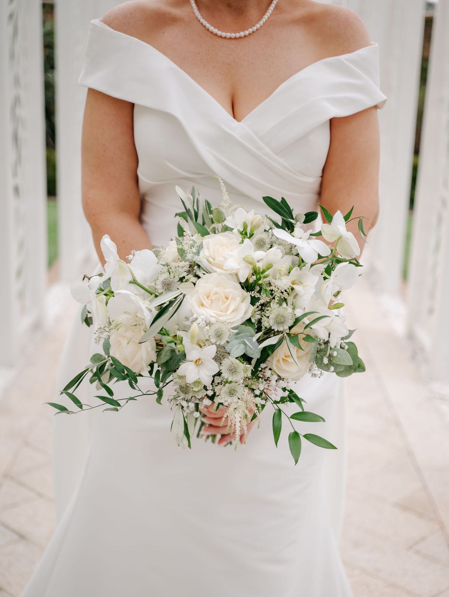 Elegant white bridal bouquet with roses and greenery.