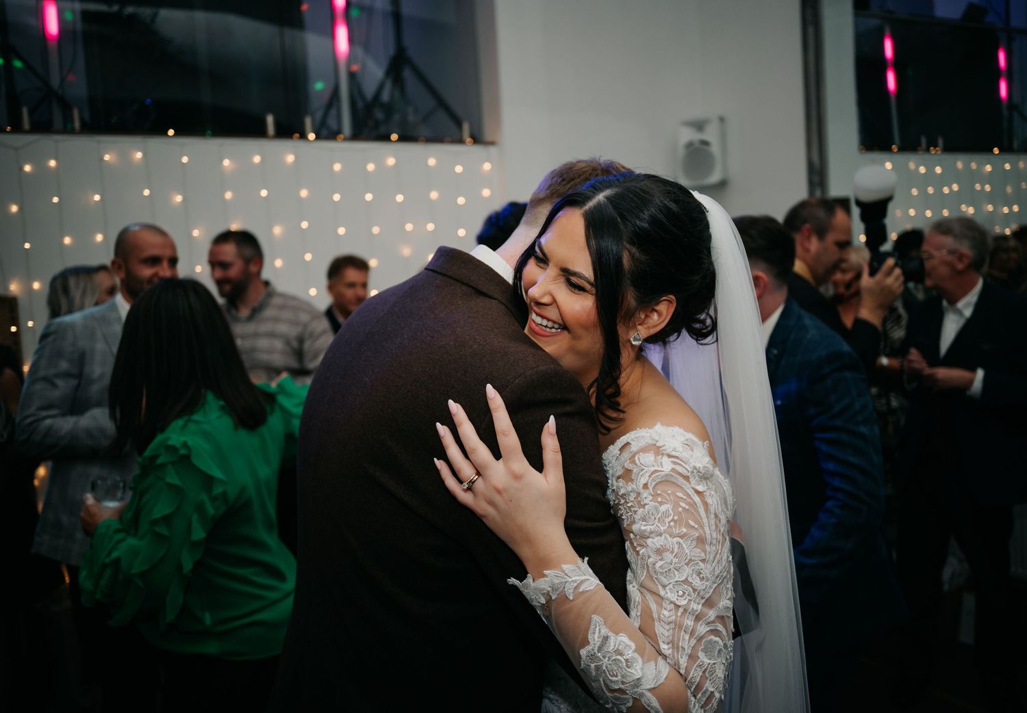 Wedding reception dance floor filled with guests celebrating under dim lighting.