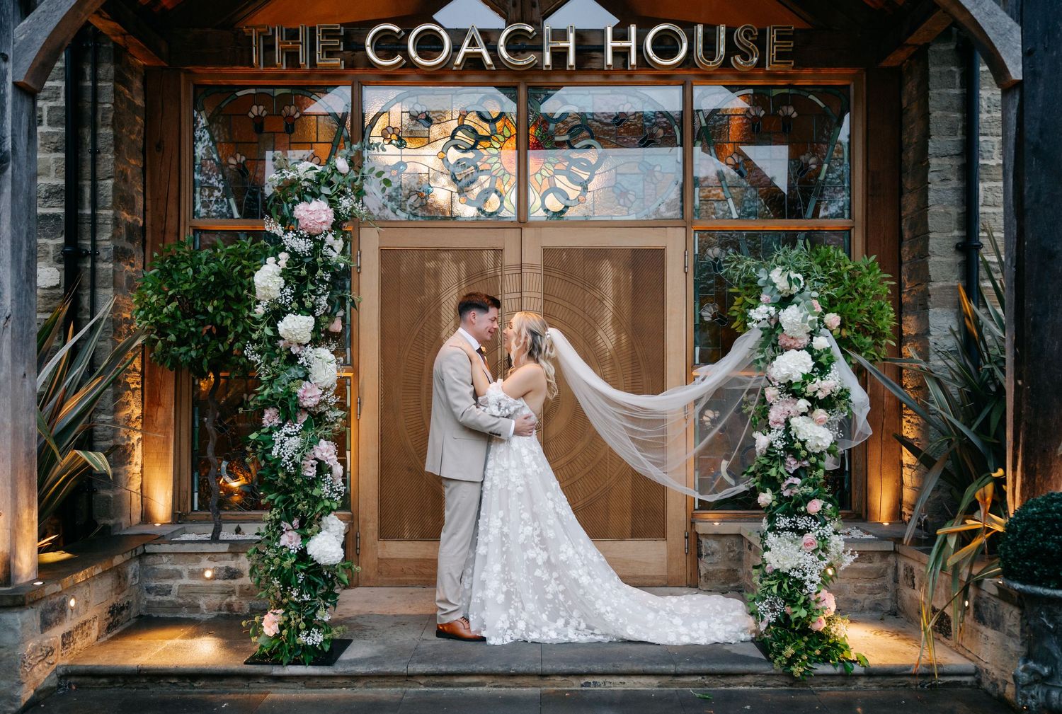 The Coach House wedding venue entrance decorated with elegant floral arrangements and signage.