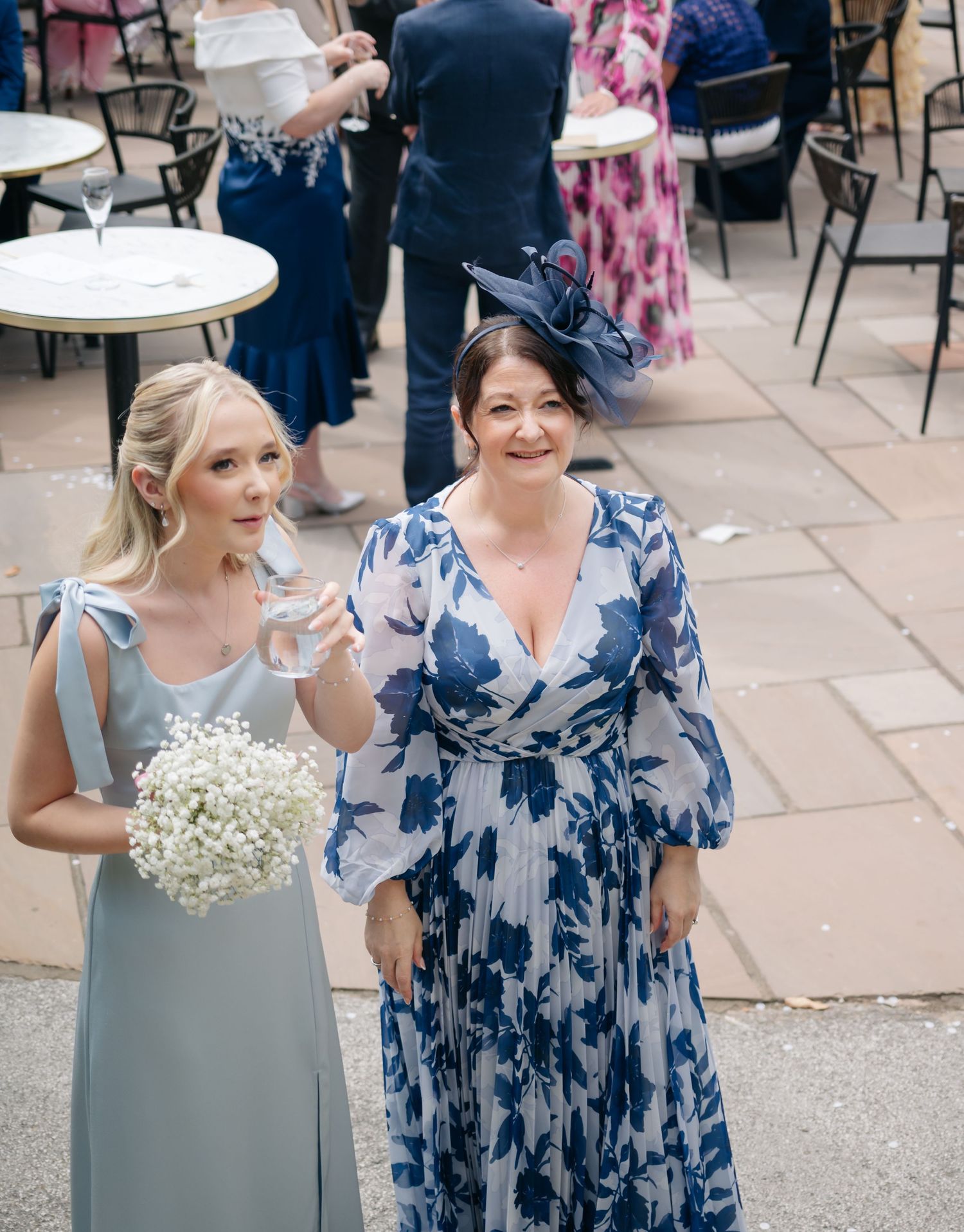 Wedding party members in navy blue and gray dresses holding white bouquets.