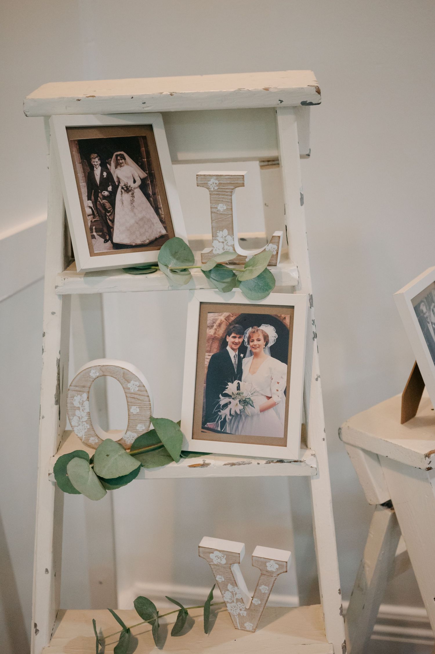 White decorative letters and frames with eucalyptus leaves arranged on display.