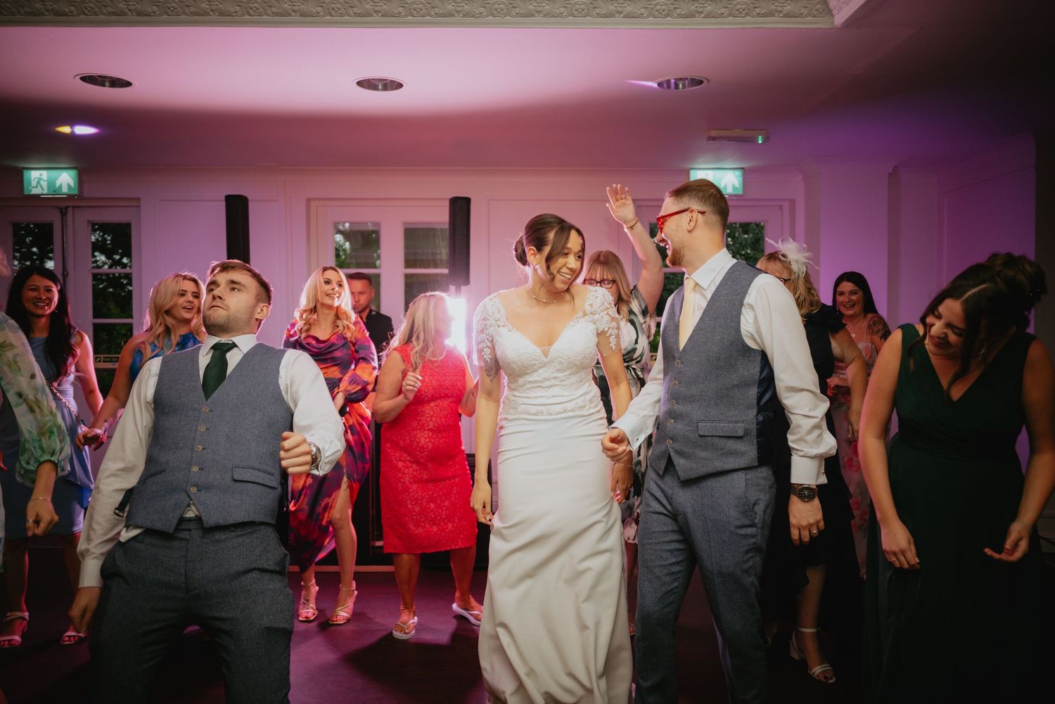 Wedding reception dance party with pink and purple lighting creating a festive atmosphere.
