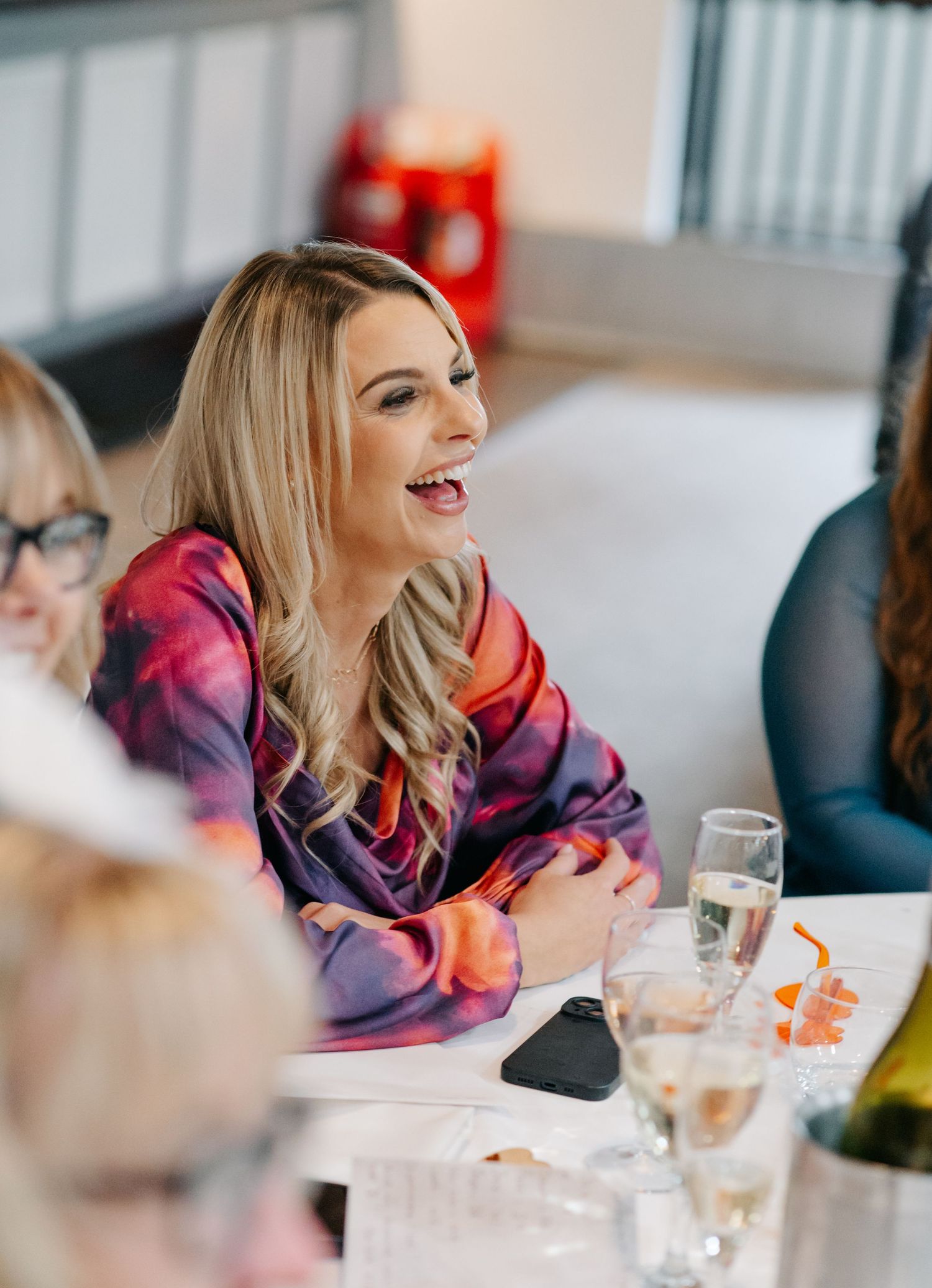 Wedding reception guests share laughter at decorated dining tables.