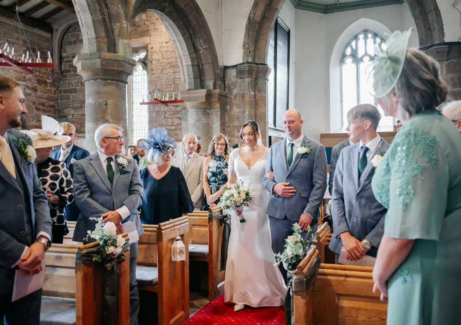 Wedding ceremony in progress at a traditional brick church with guests seated in wooden pews.