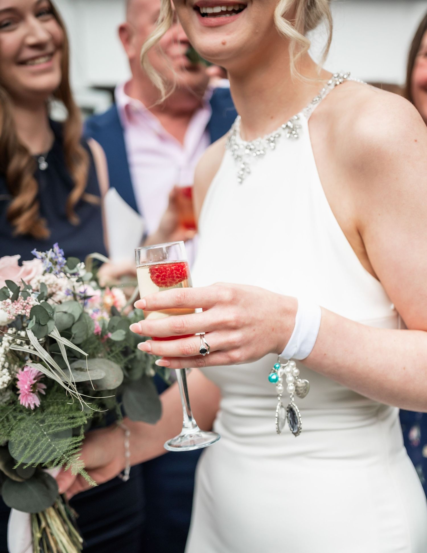 Wedding celebration with bouquet and champagne toast in elegant outdoor setting.
