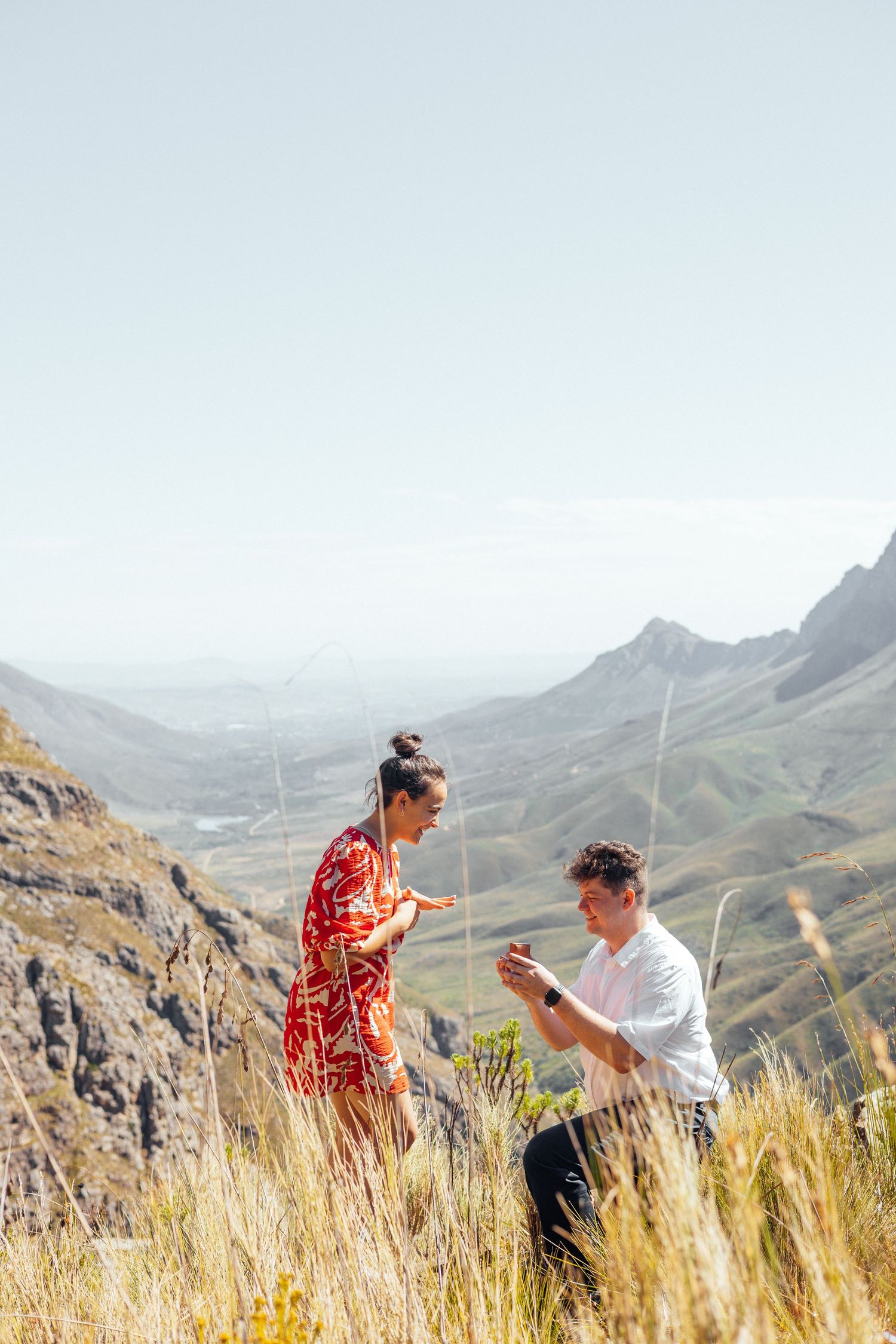 A surprise proposal unfolds on a mountainside with dramatic valley views in the background.