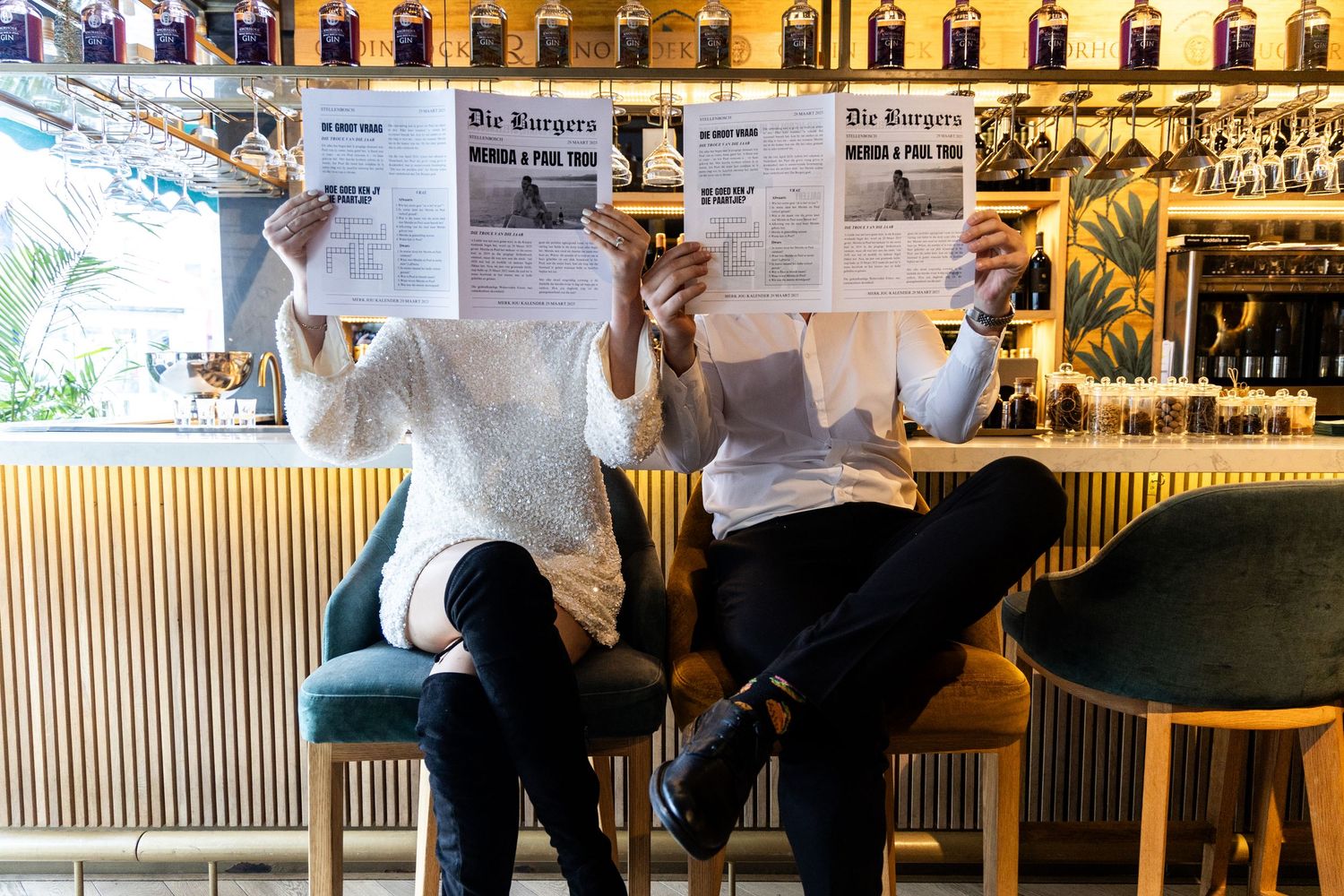 People reading newspapers while sitting at a modern bar with wooden accents.
