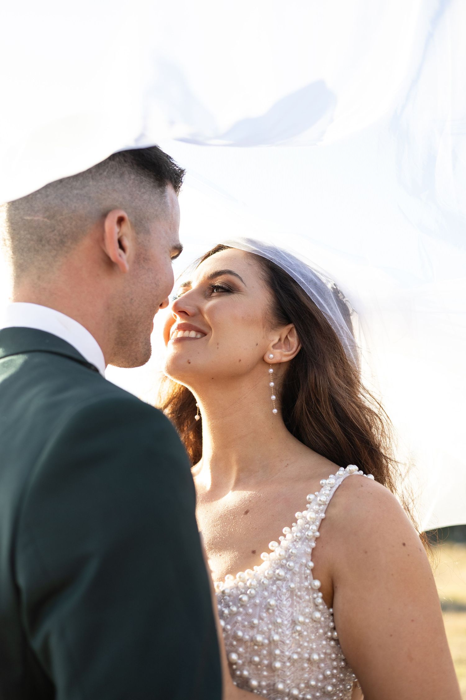 A romantic wedding couple shares an intimate moment in beautiful golden sunlight.