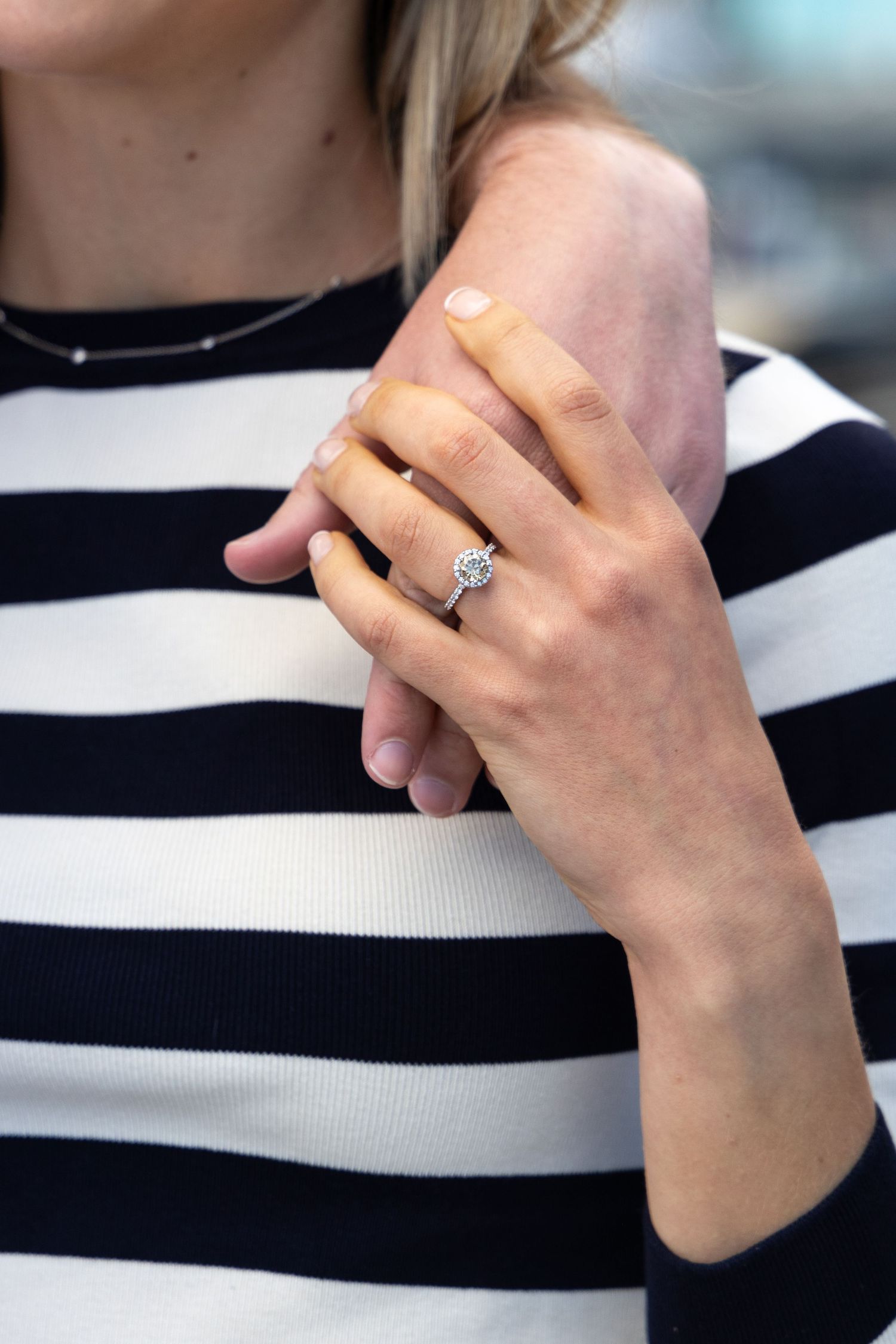 Close-up of diamond engagement ring on striped sweater.