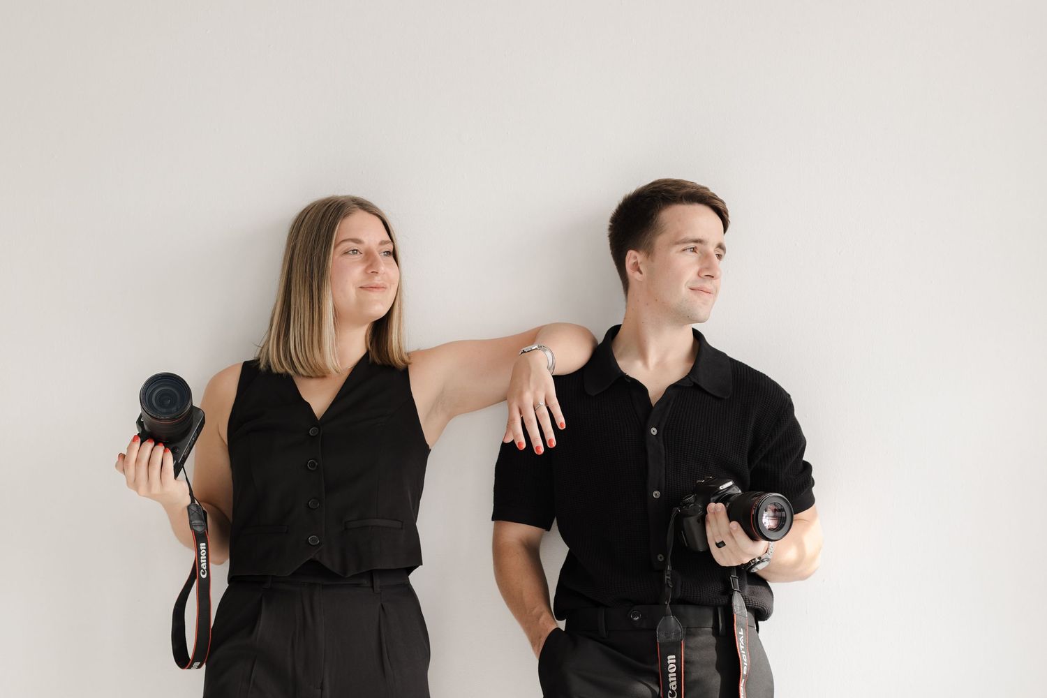 Creative photographers in coordinated black outfits pose with their professional equipment.