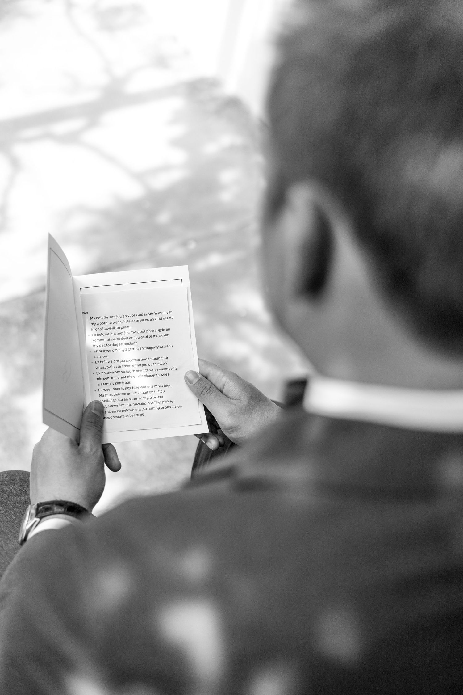 Over-the-shoulder view in black and white of someone reading a printed document or paper.