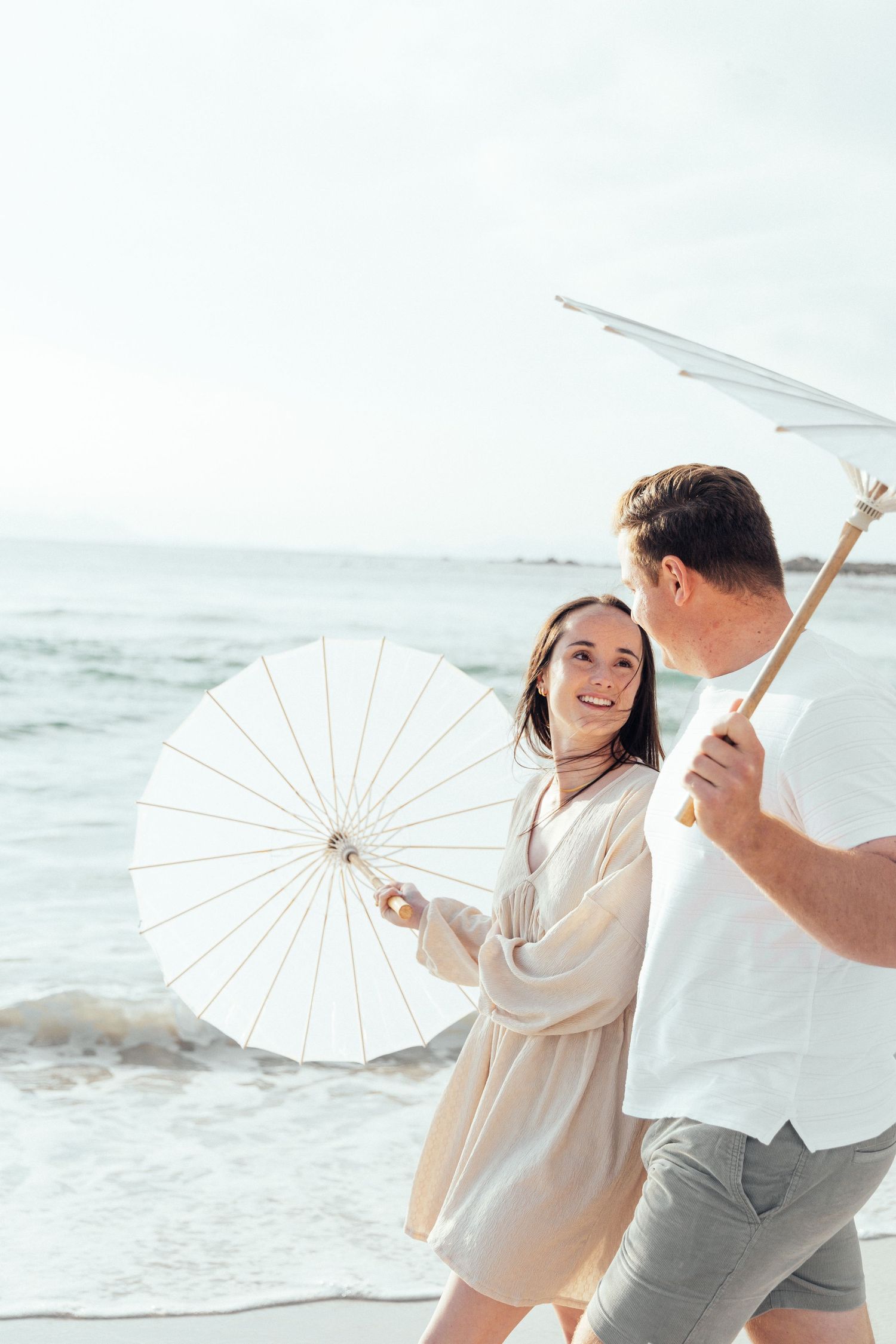 A couple playing with parasols on a misty beach.
