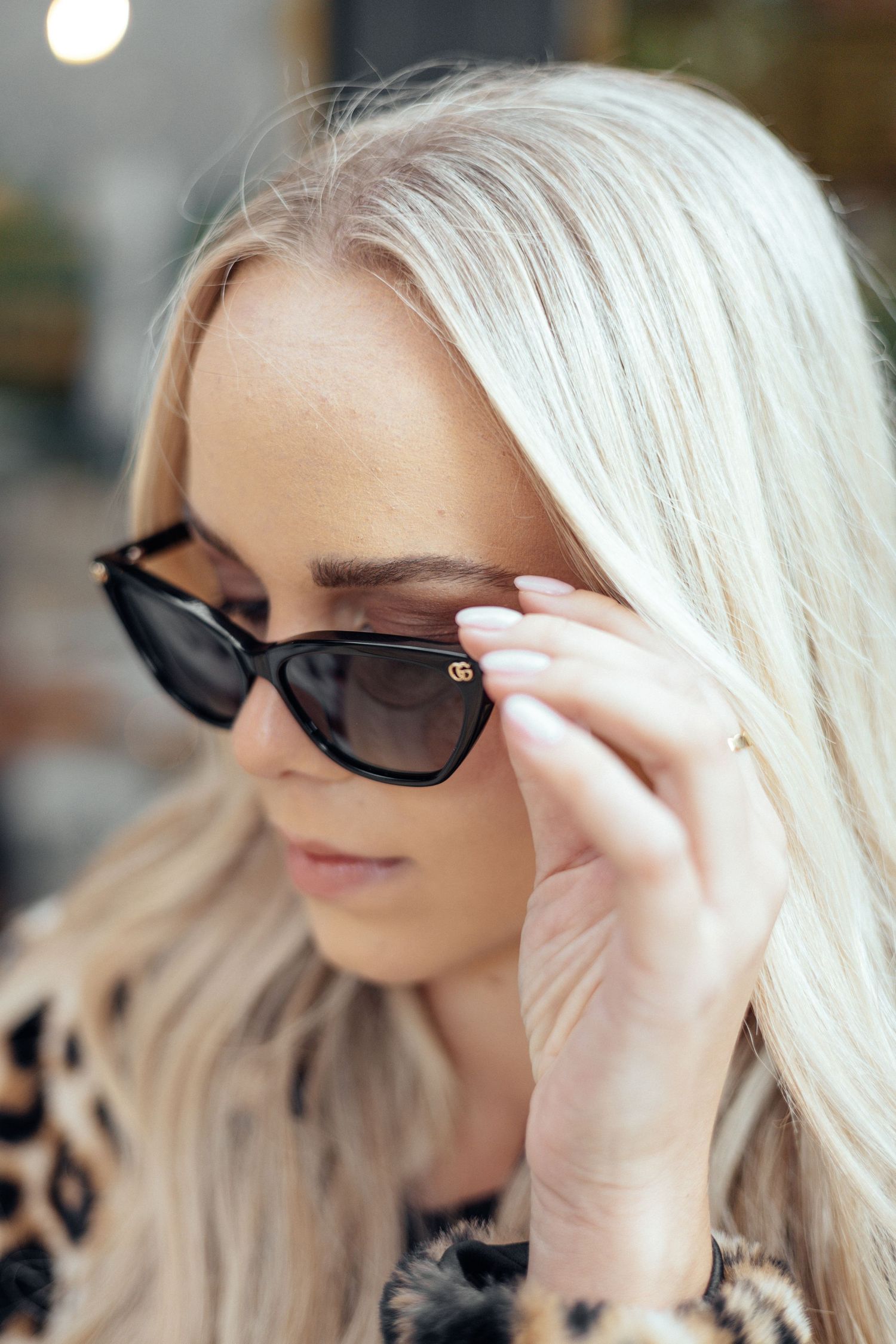 Close up profile view of platinum blonde hair and black sunglasses with hand adjusting frames.