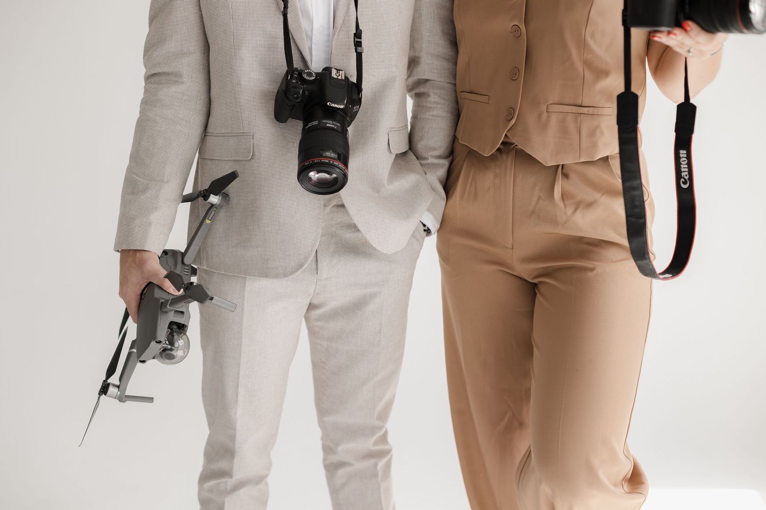 Photographers in contrasting beige and gray suits holding professional cameras.