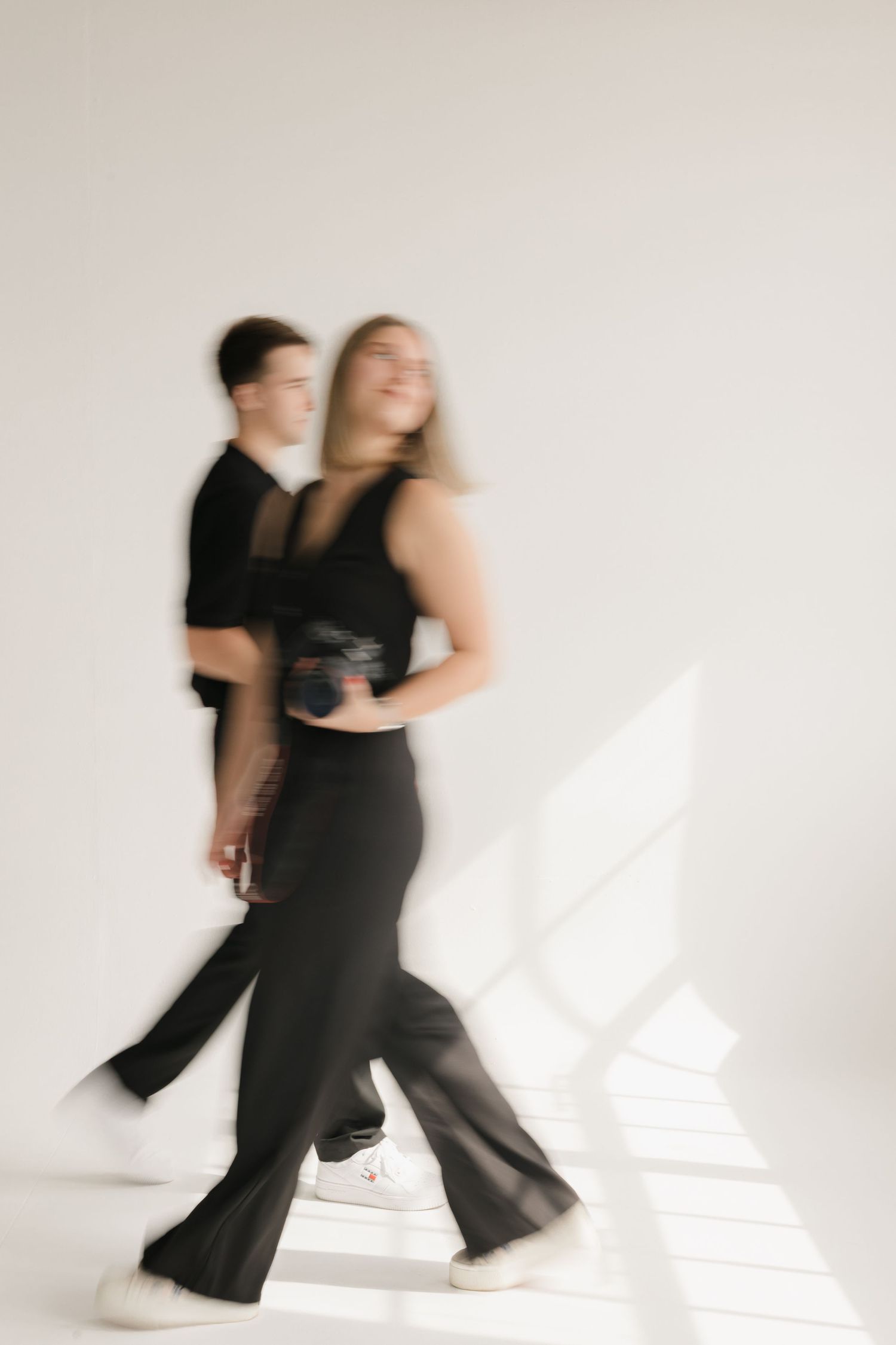 Abstract motion blur photo of dancers in black attire against white background.