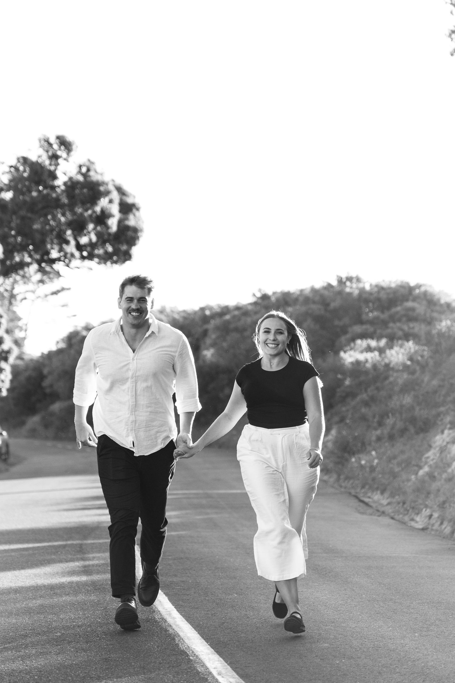 Couple walking together on paved road in casual black and white outfits.