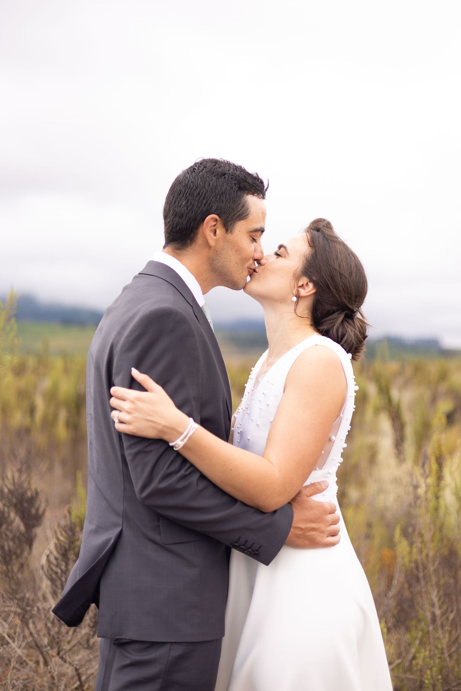 Romantic wedding portrait in rustic field with couple sharing intimate moment.