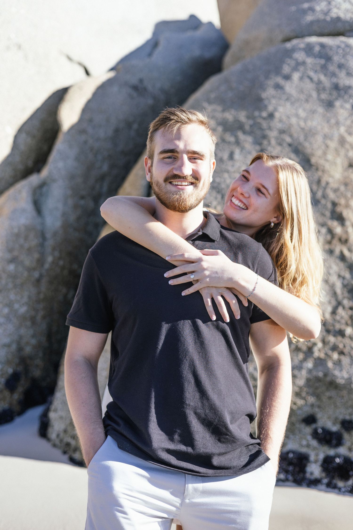 Joyful couple sharing a happy moment together on a rocky beach.