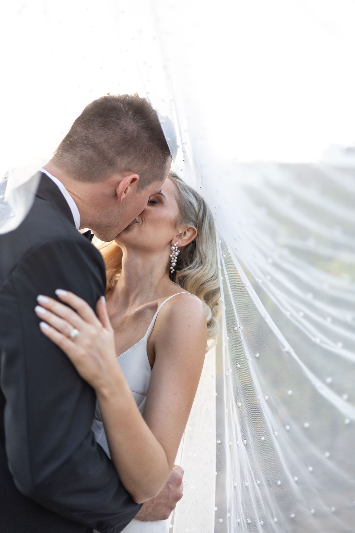 Close-up shot of couple sharing romantic moment under sparkly wedding veil.