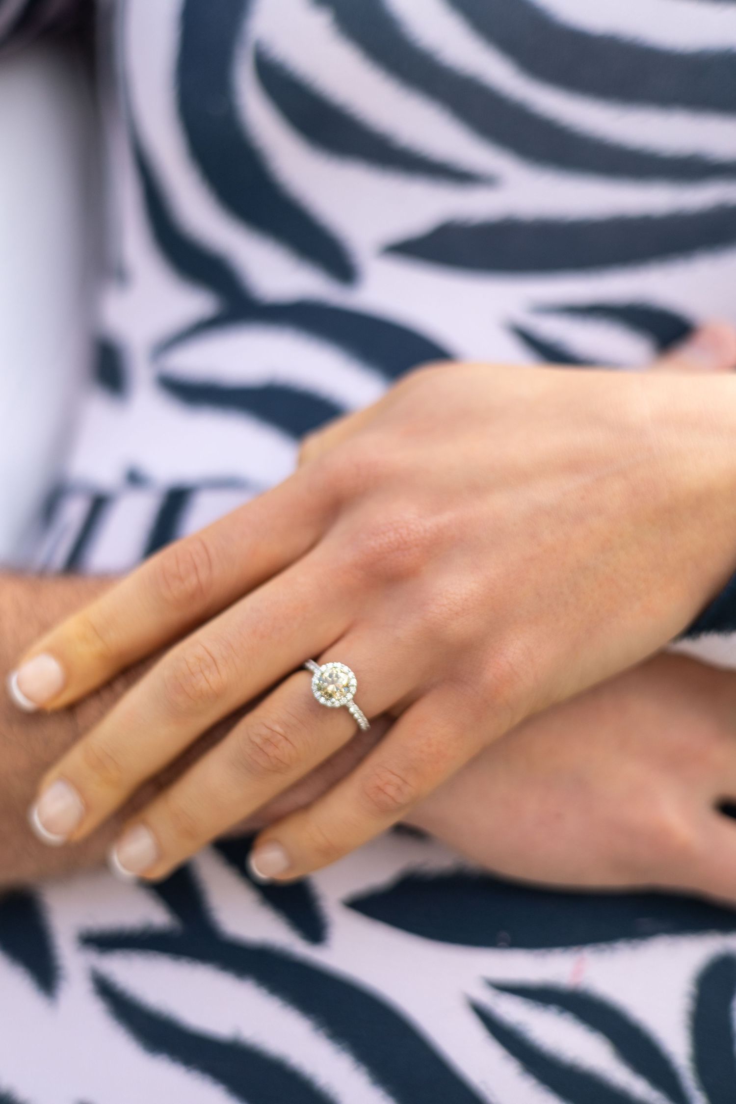 Close up of an elegant solitaire diamond engagement ring on a manicured hand.