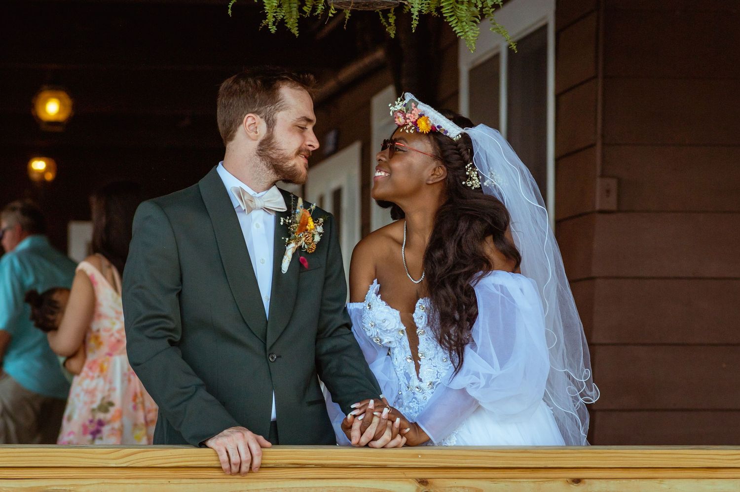 A couple shares an intimate moment on their wedding day on a balcony at sunset.