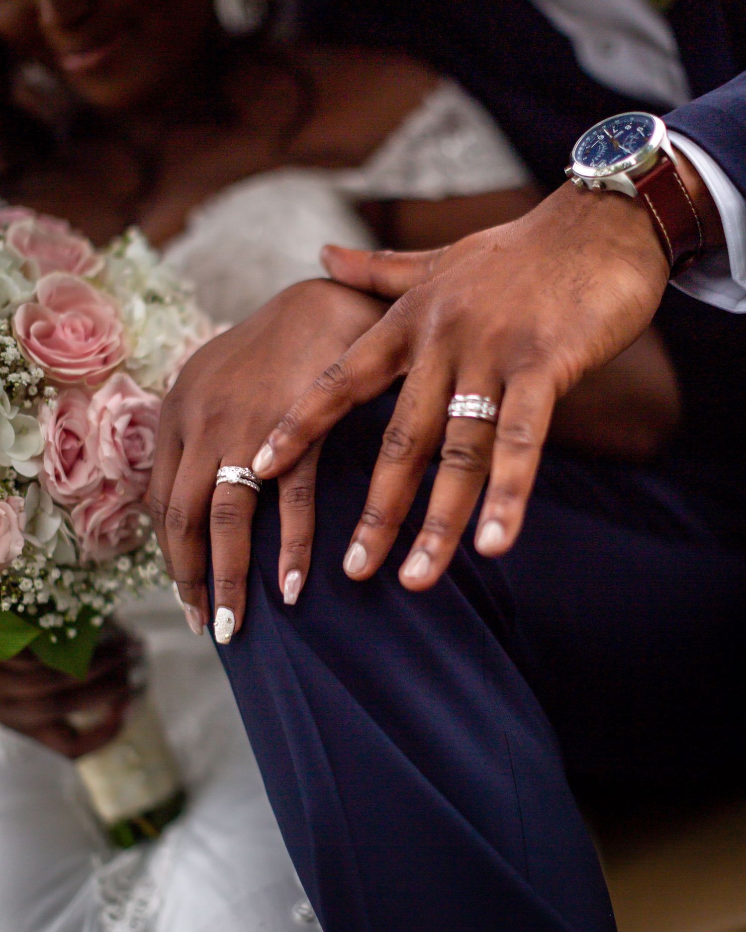 Wedding rings and watch detail shot with pink roses and delicate manicure.