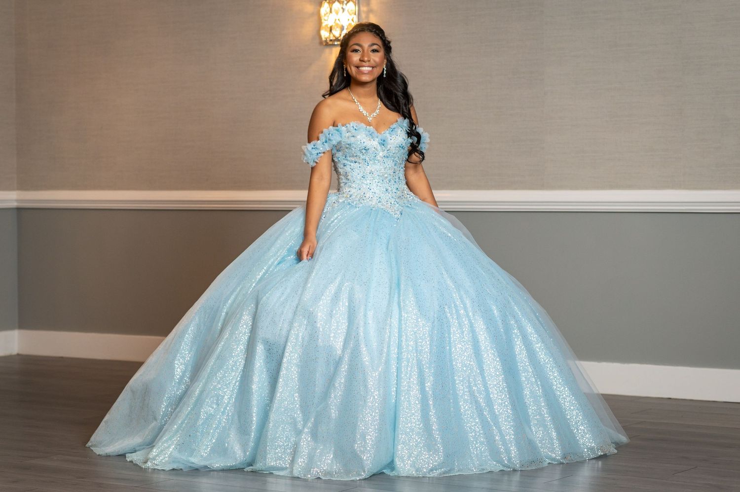 Stunning light blue ballgown with sparkling details and off-shoulder design in formal photo setting.