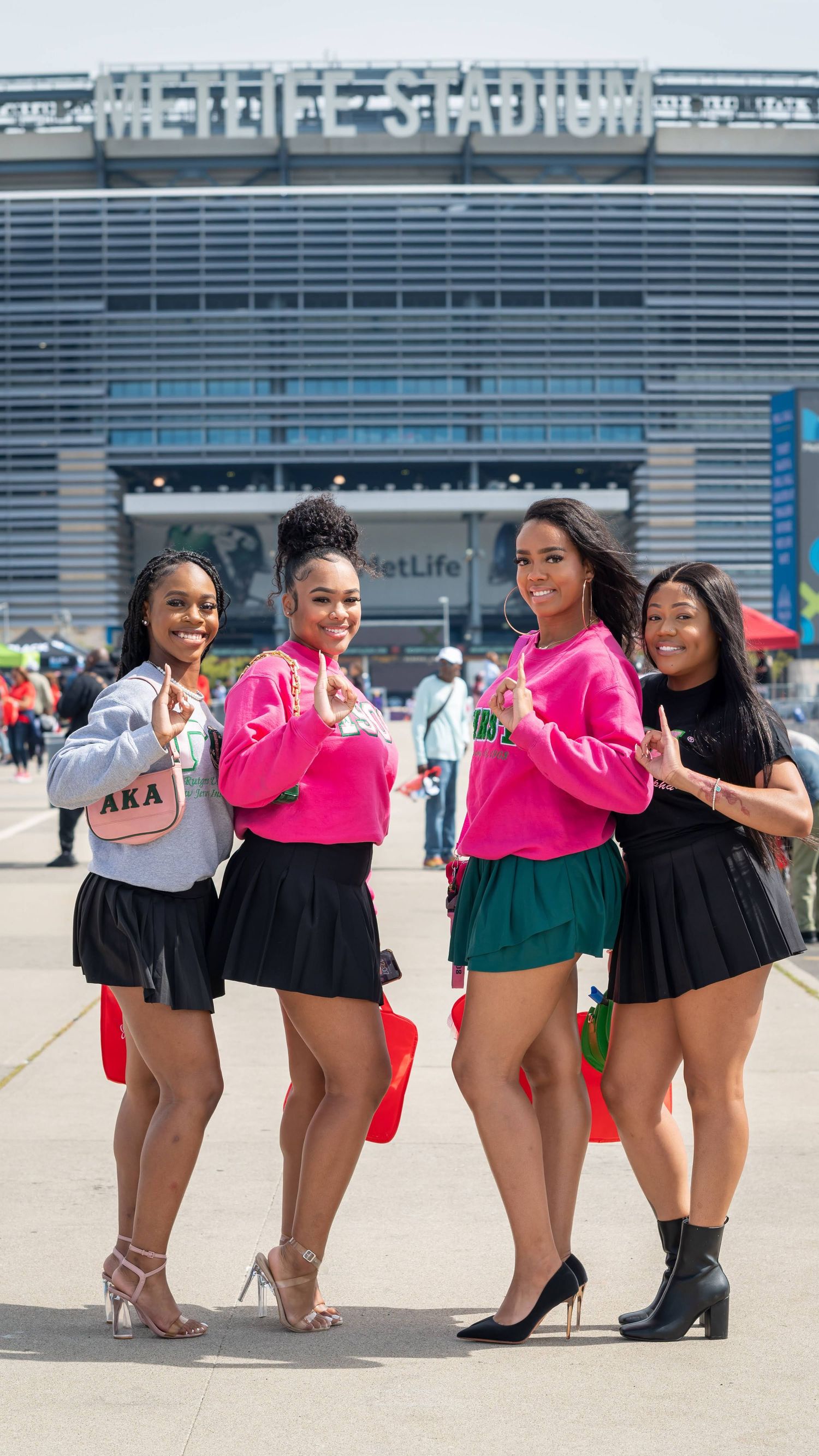 Four friends pose together in coordinated outfits outside MetLife Stadium.