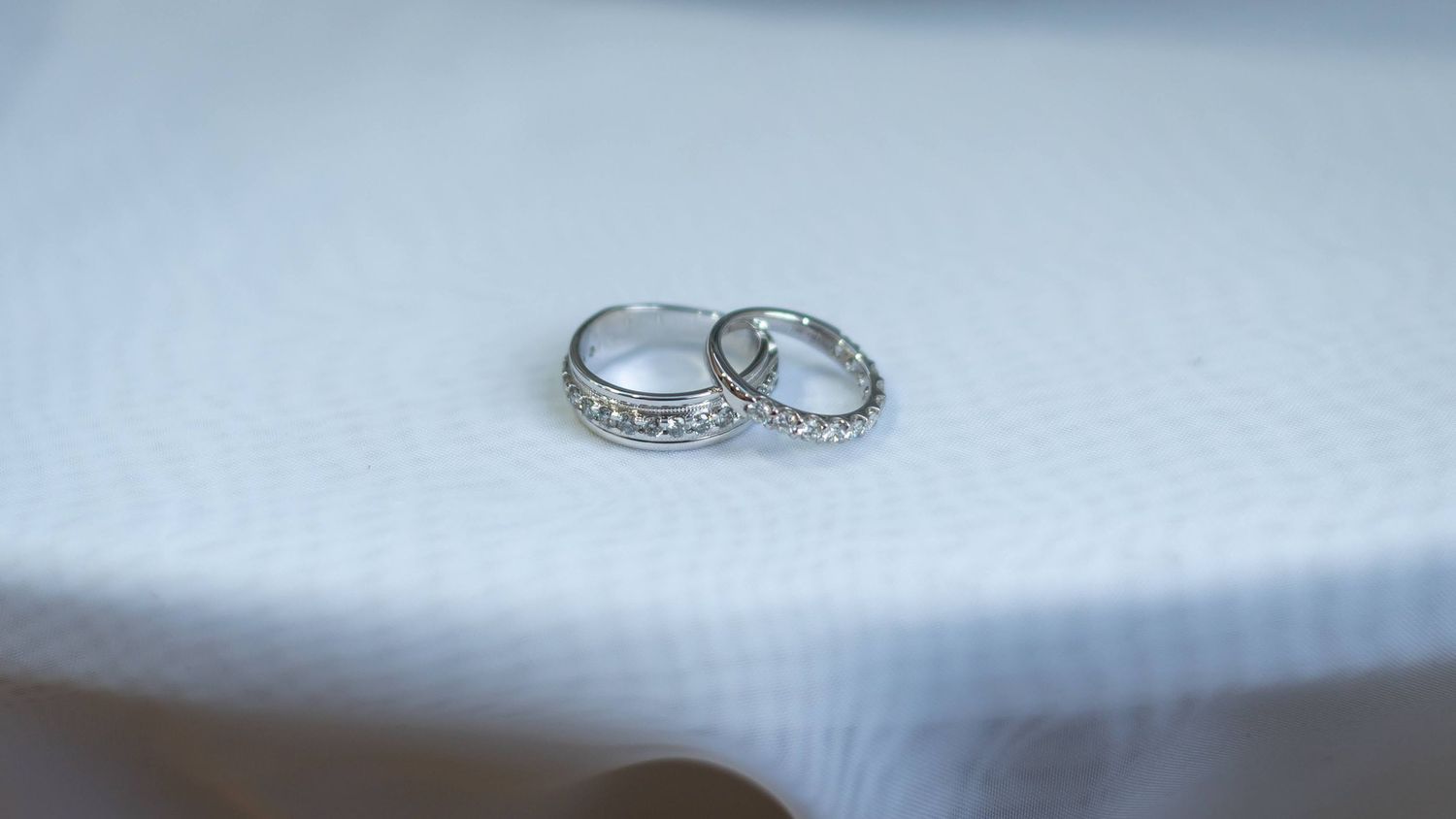 Two diamond-encrusted wedding bands photographed on a white surface.