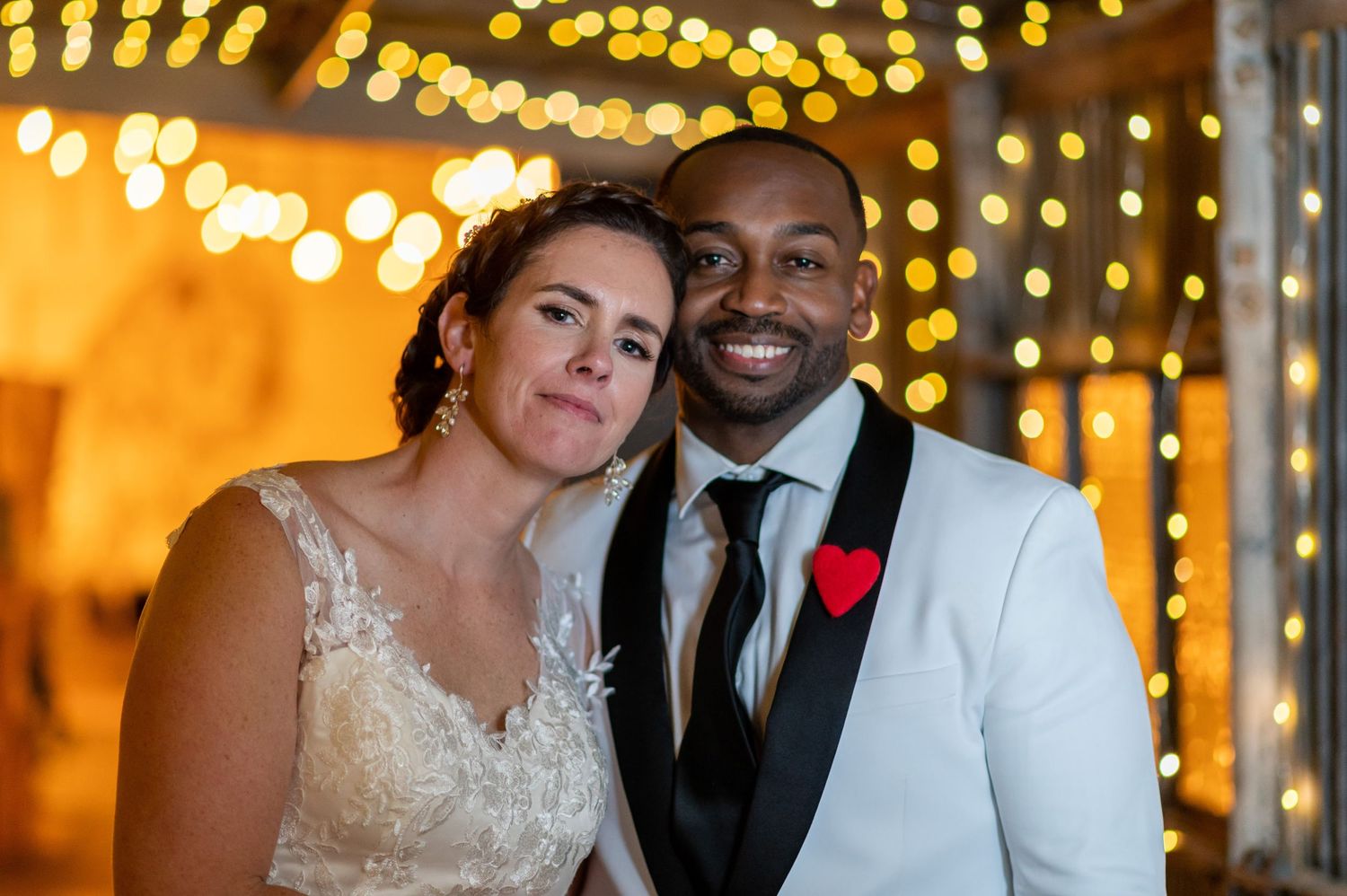 Romantic wedding portrait with twinkle lights creating bokeh effect in background.