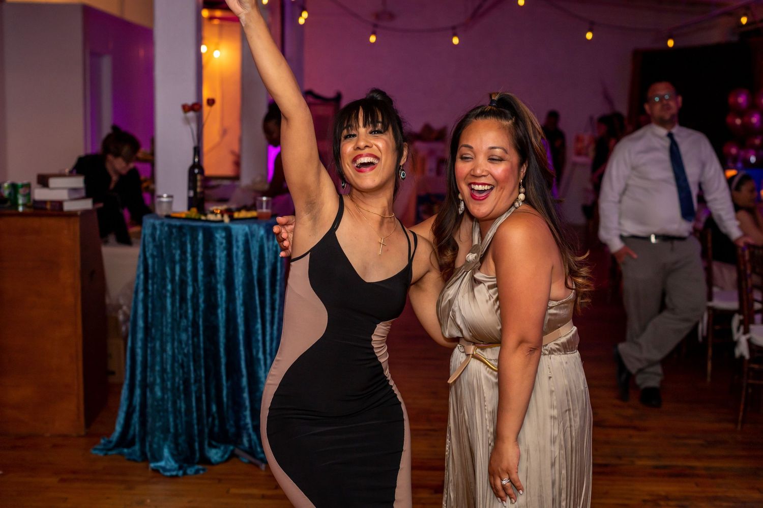 Party scene with people dancing enthusiastically on a wooden dance floor.